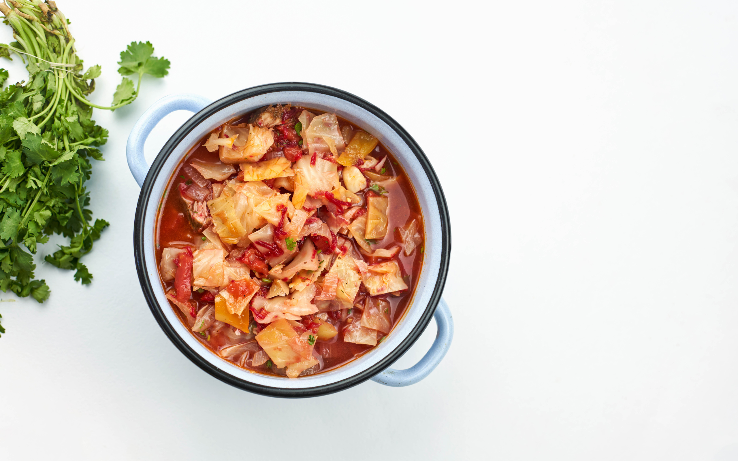 Горячие щи в кастрюле на столе с петрушкой