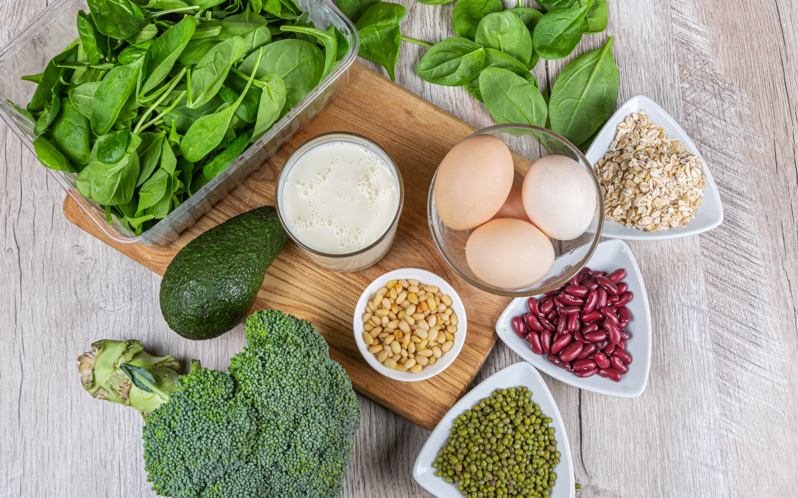 Бобовые, авокадо, базилик, яйца молоко и брокколи на столе