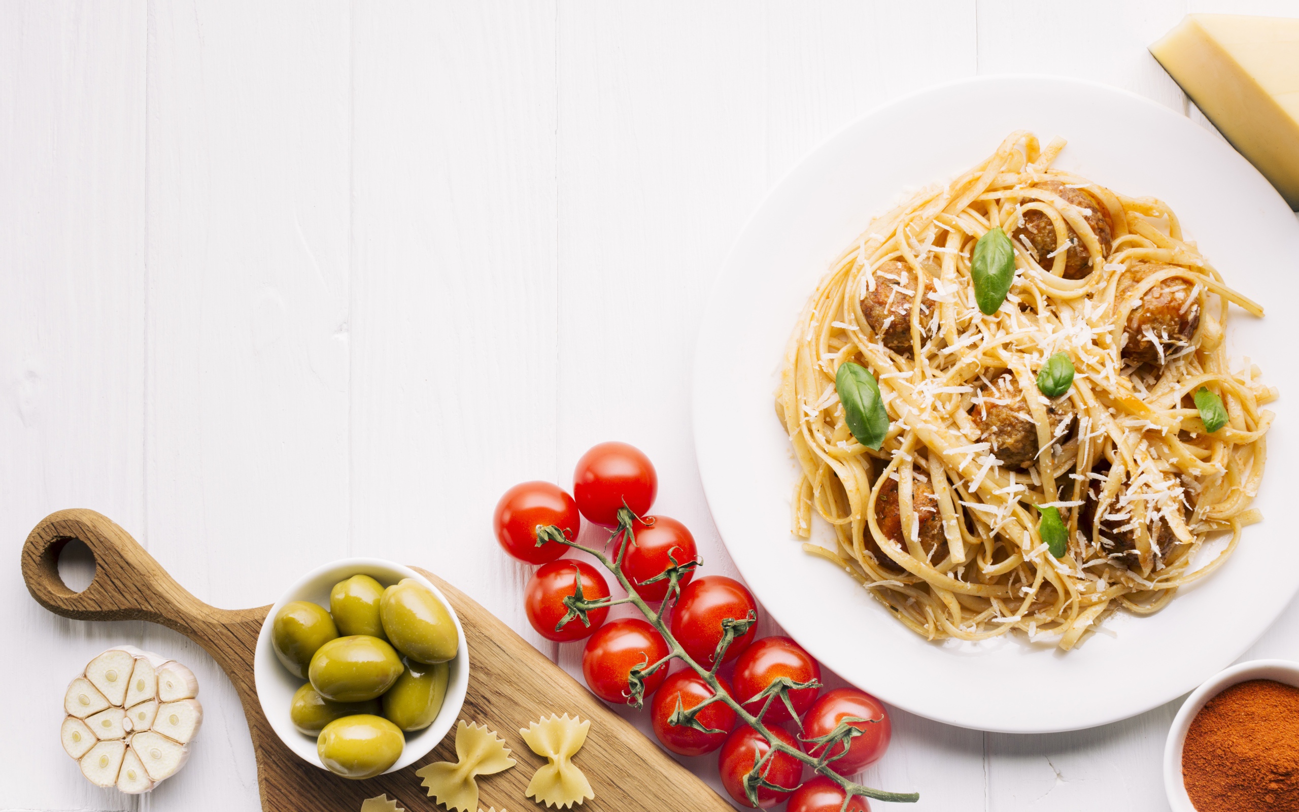 Паста с фрикадельками на столе с помидорами и оливками