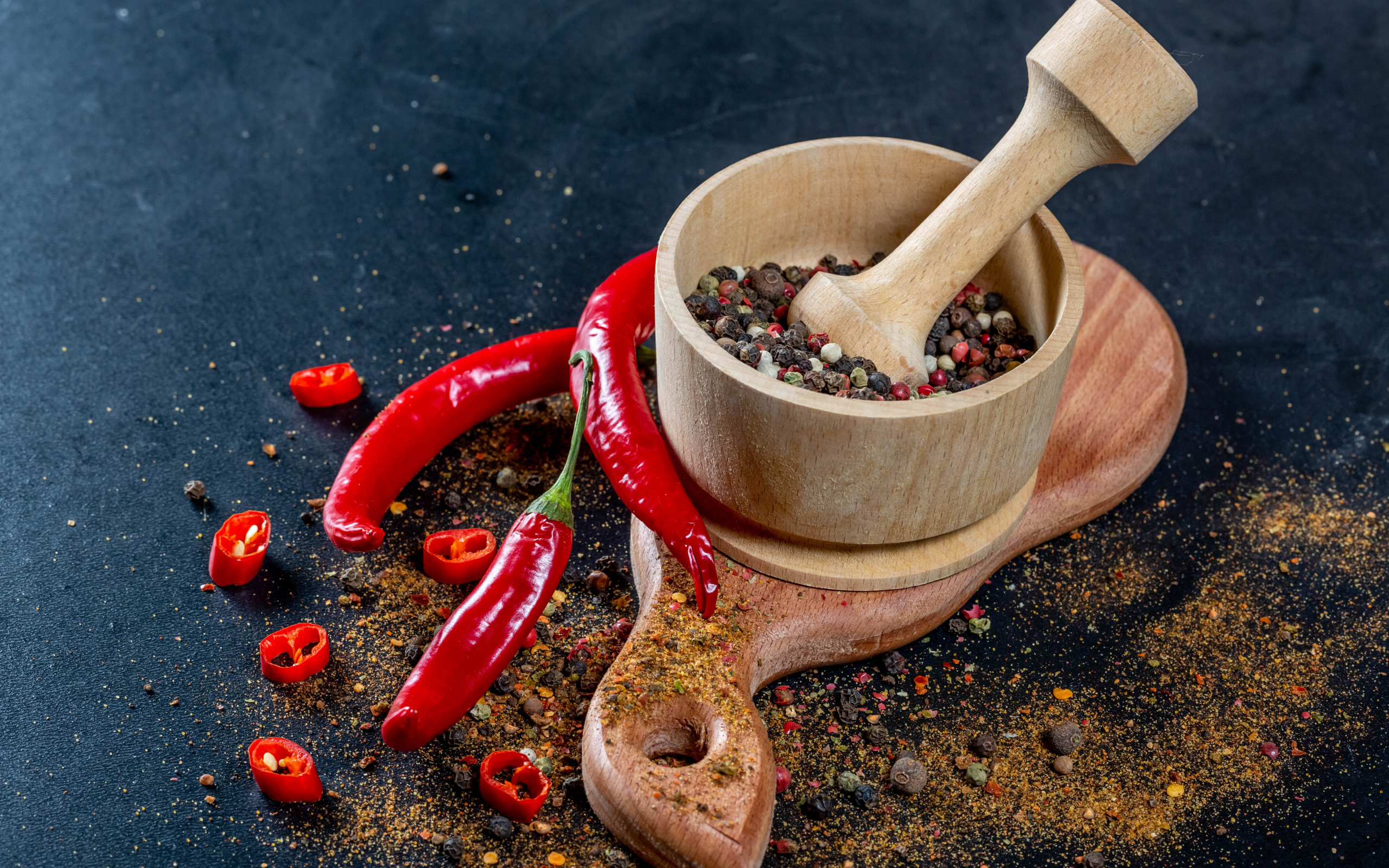 Перец горошком в ступке на столе с острым перцем