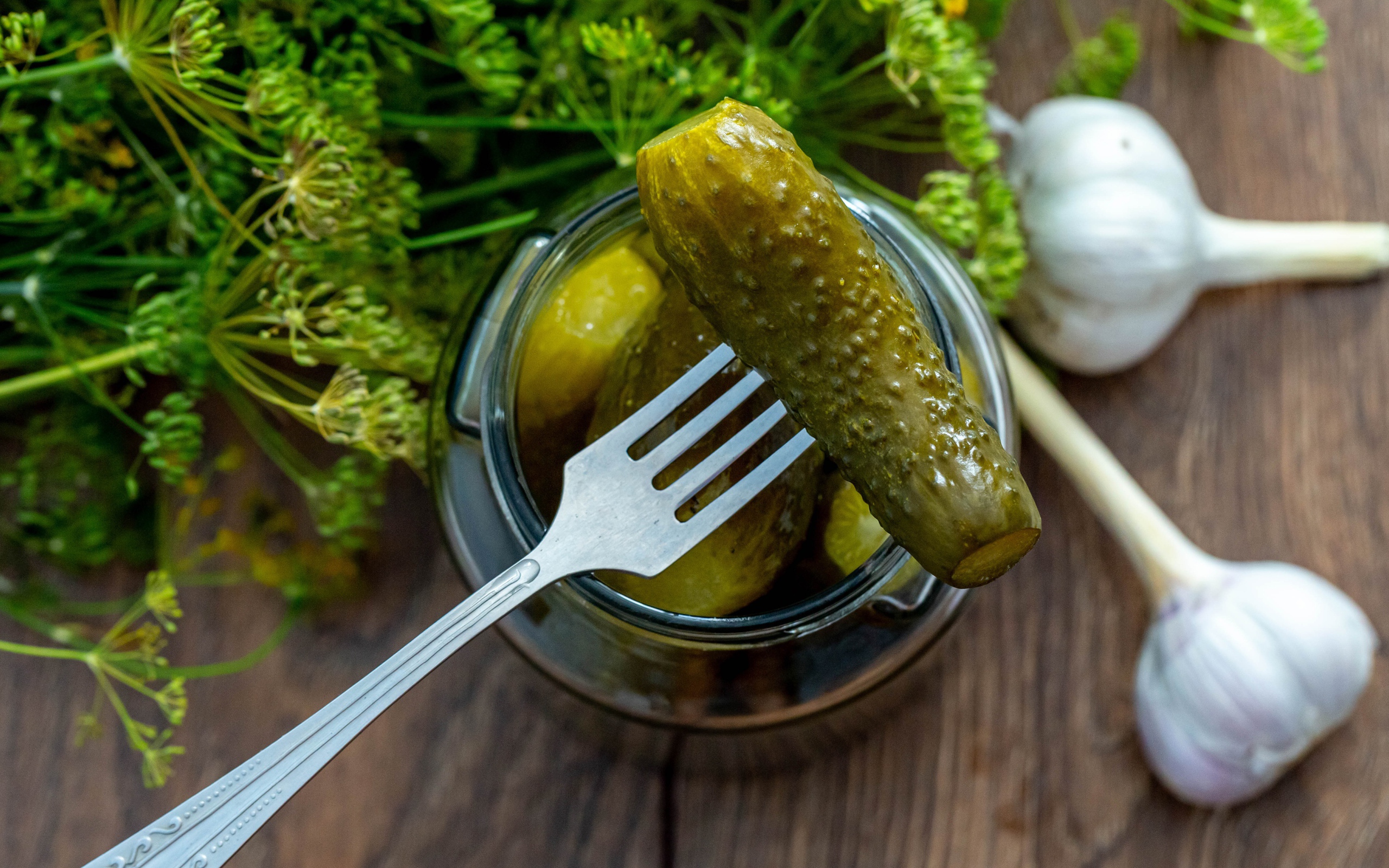 Маринованные огурцы в банке на столе с чесноком и укропом