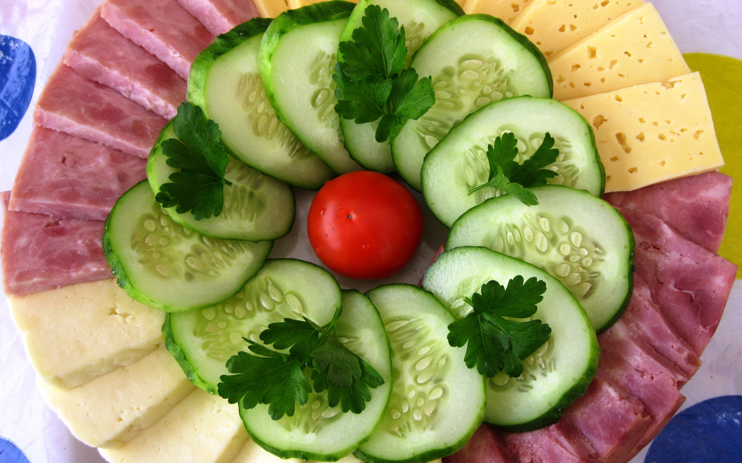 Сыр нарезанный, огурцы и ветчина на тарелке 
