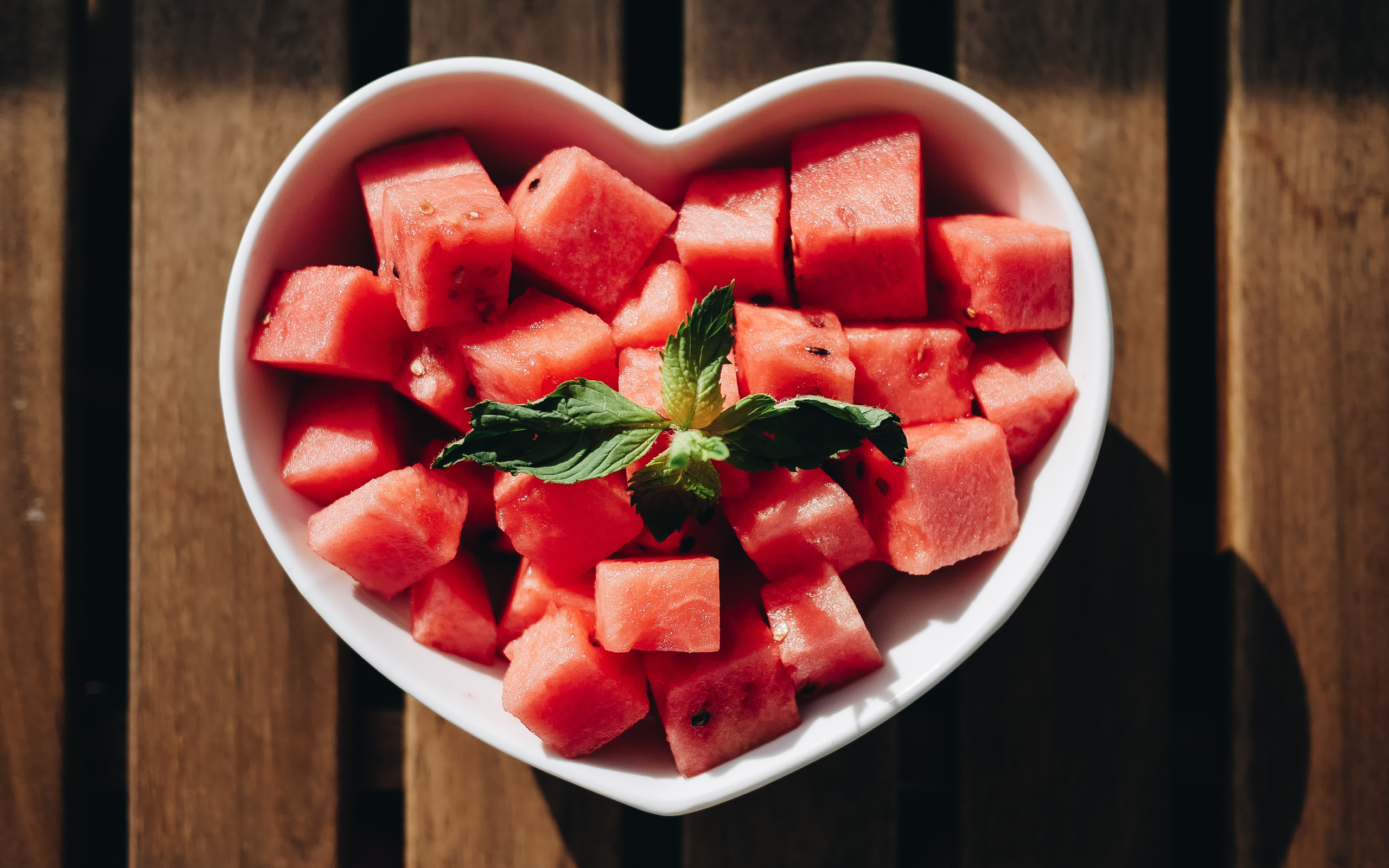 Нарезанный кубиками арбуз в белой тарелке в форме сердца