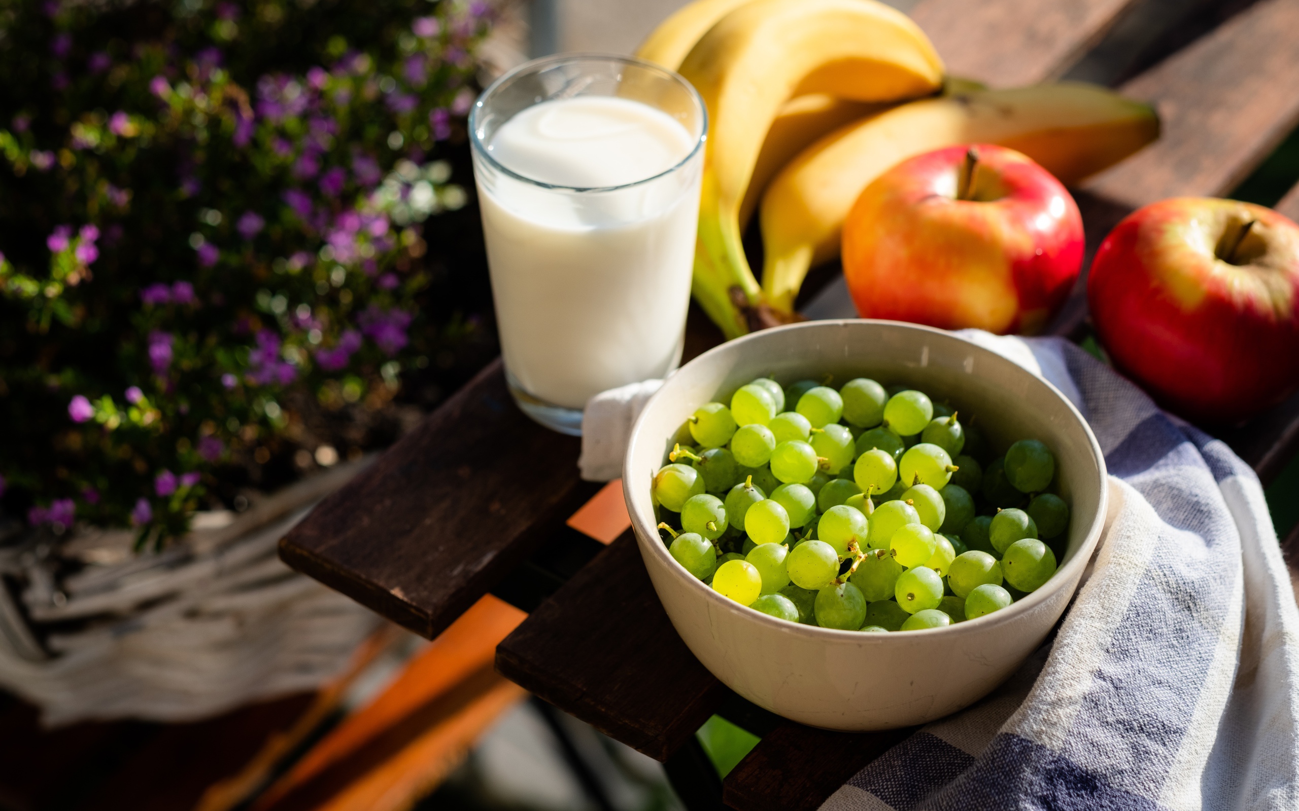 Зеленый виноград на столе с бананами, яблоками и молоком