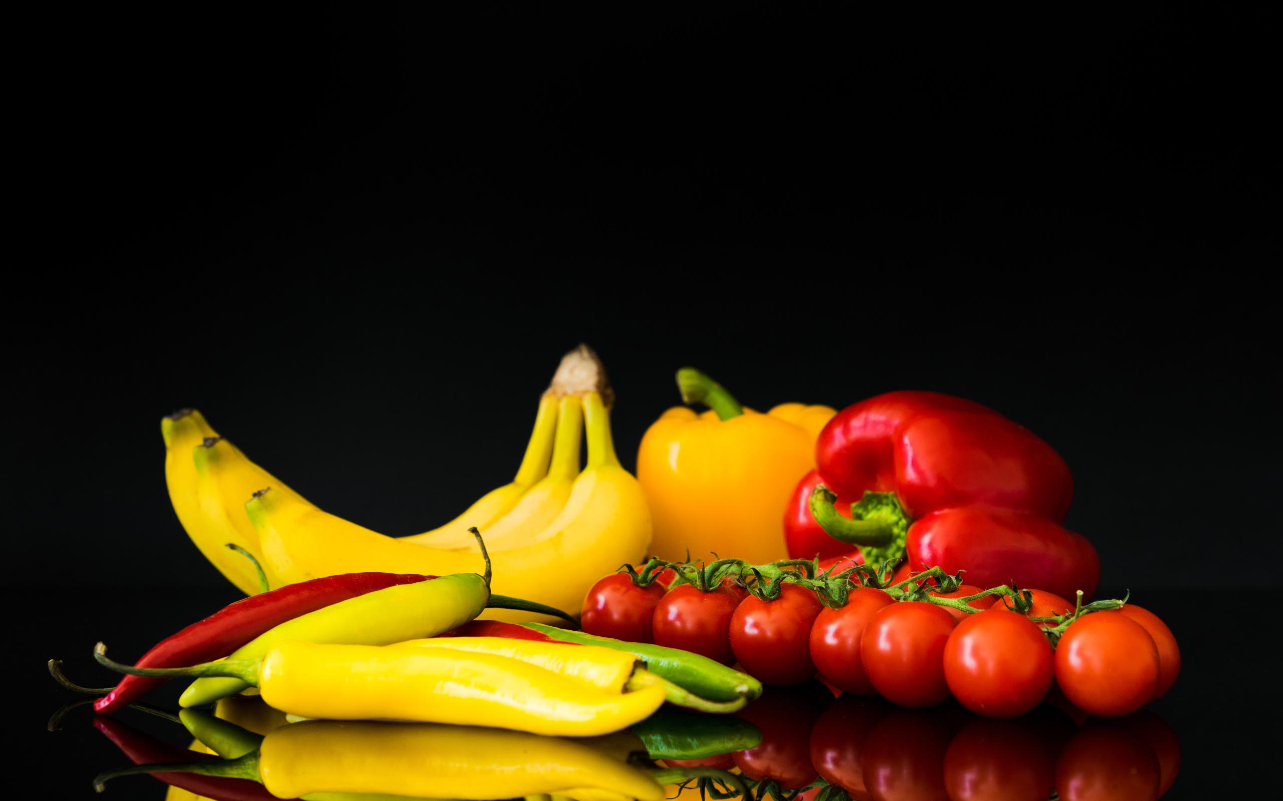 Перец, помидоры и бананы на черном фоне