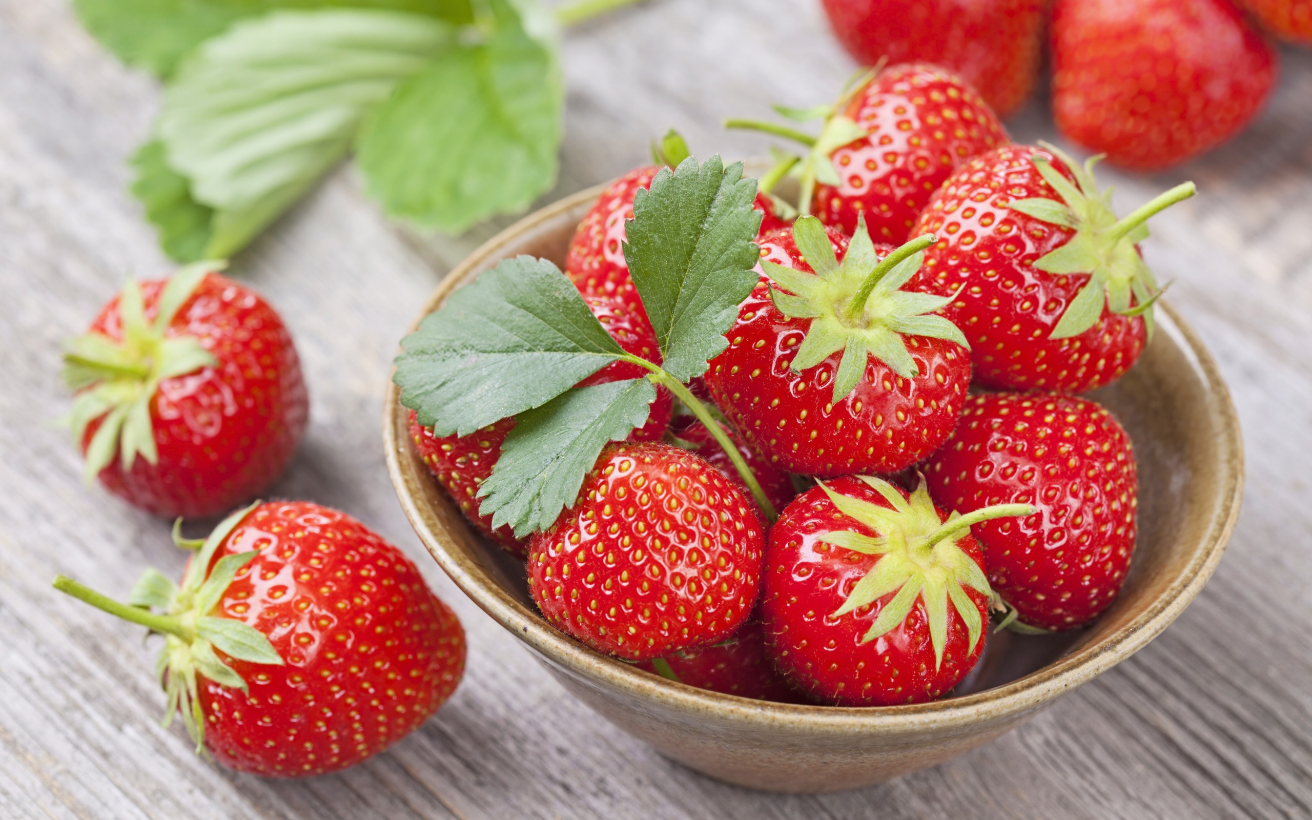 Красная спелая сладкая клубника в тарелке с зелеными листьями