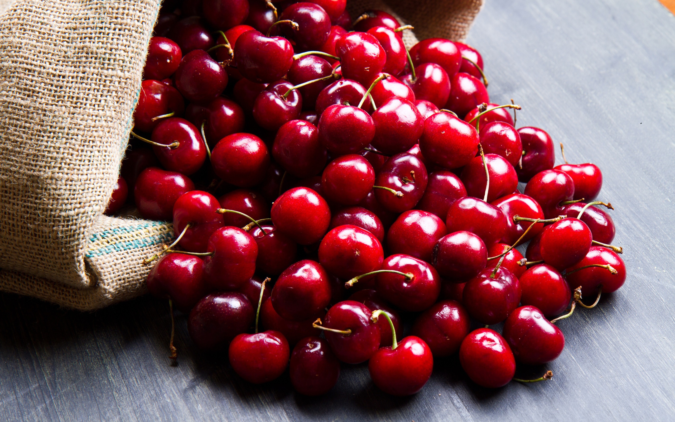 Спелые красные черешни в мешке на столе 