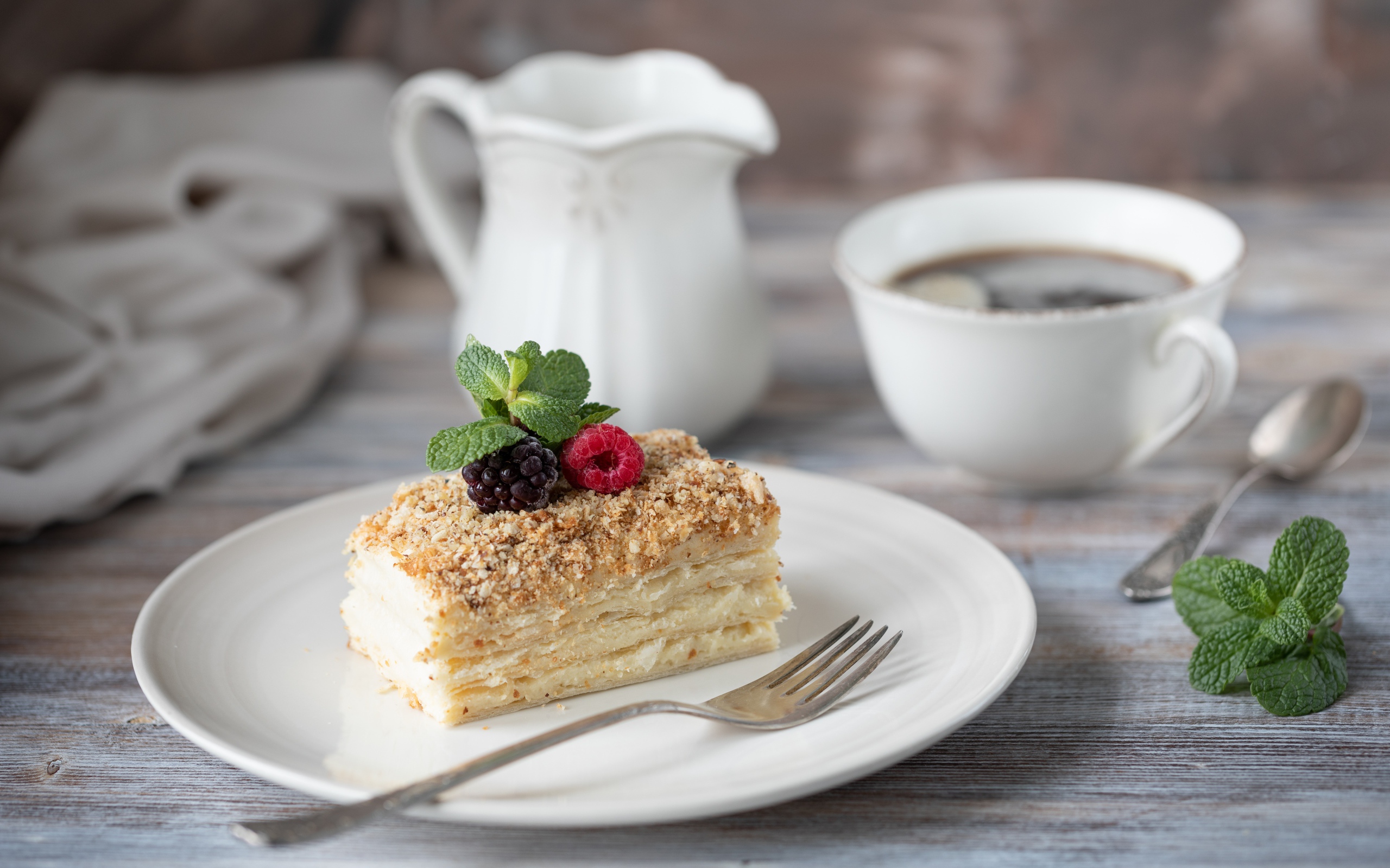 Кусок торта лежит на белой тарелке на столе с кофе