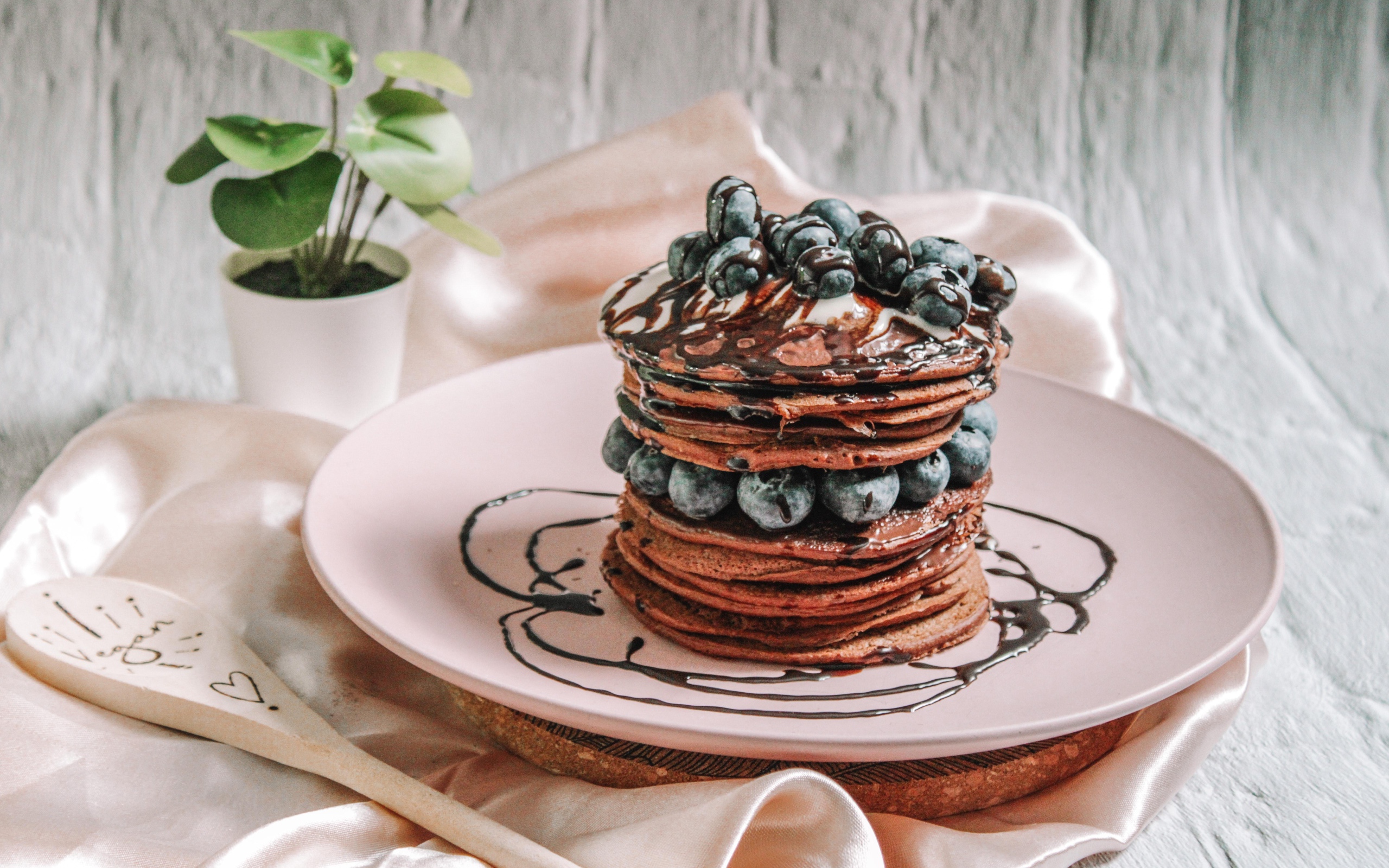 Шоколадные оладьи с ягодами черники на белой тарелке