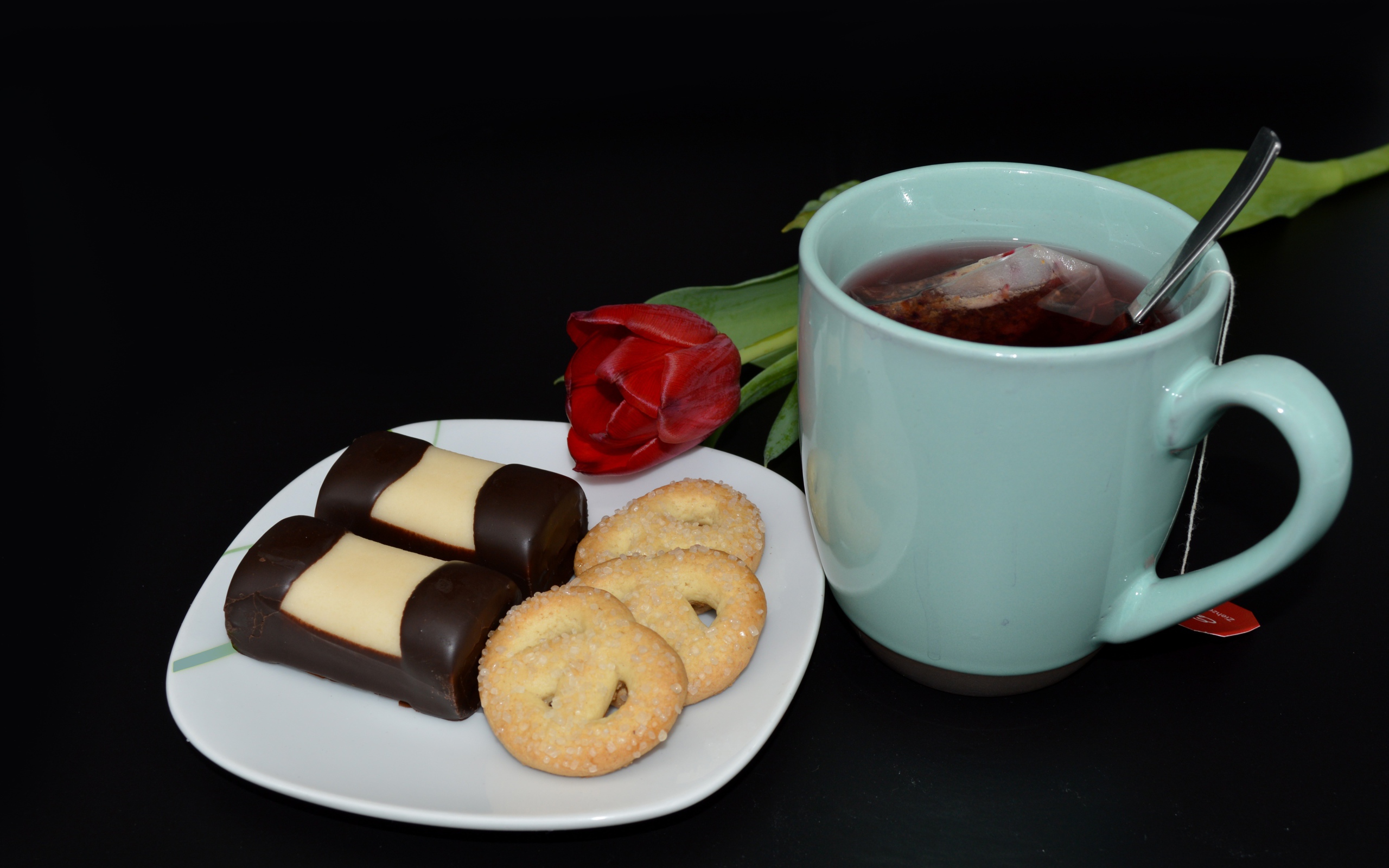 Печенье с конфетами на столе с чашкой чая и тюльпаном