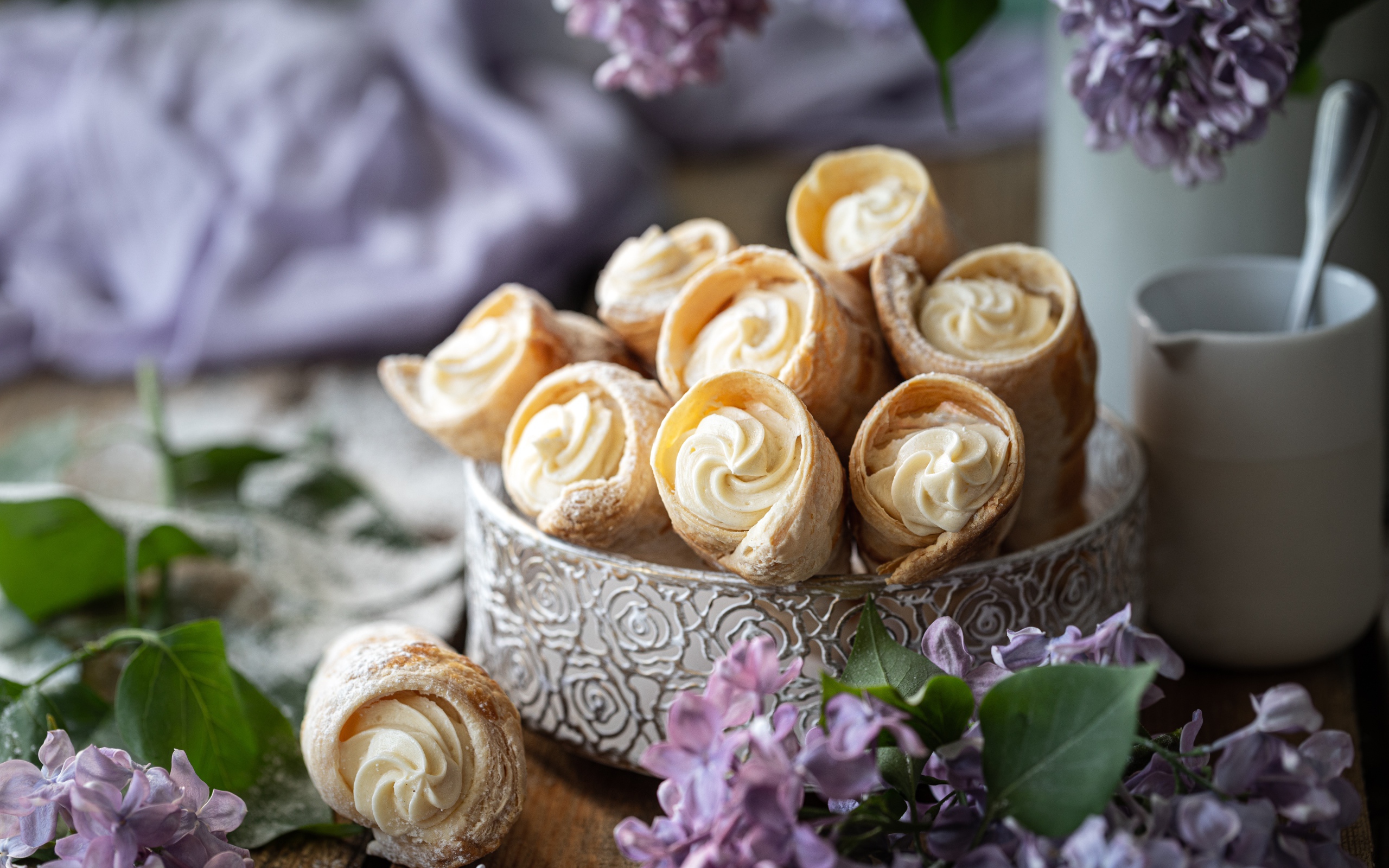 Трубочки с кремом на столе с цветами сирени