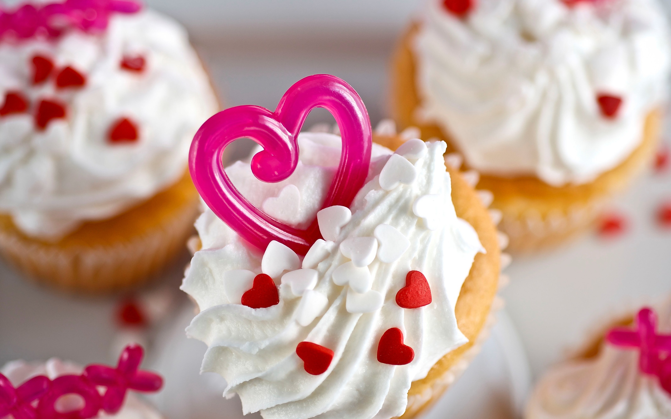 Кексы с кремом и сердечками на столе 