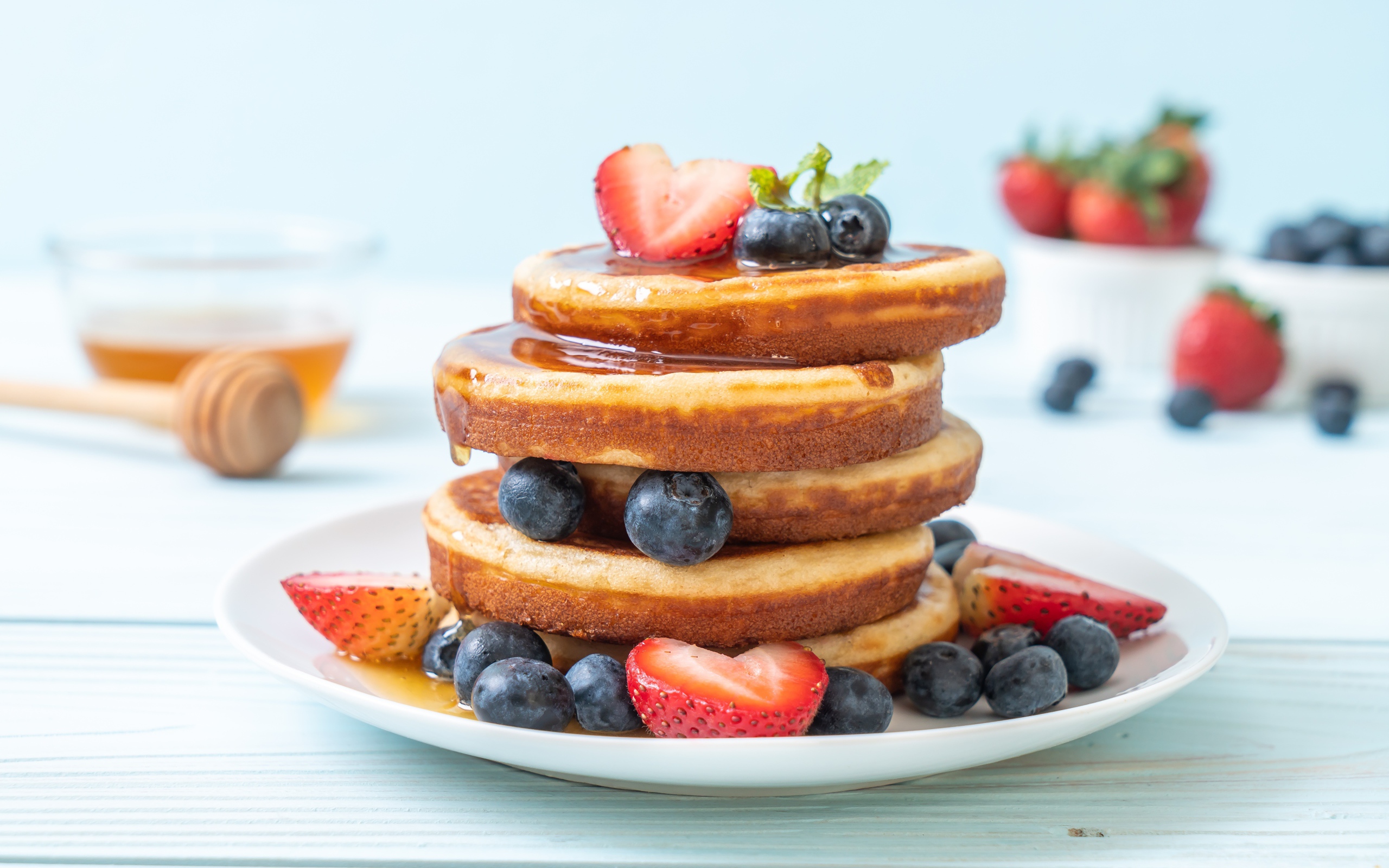 Lush pancakes with blueberries, strawberries and honey
