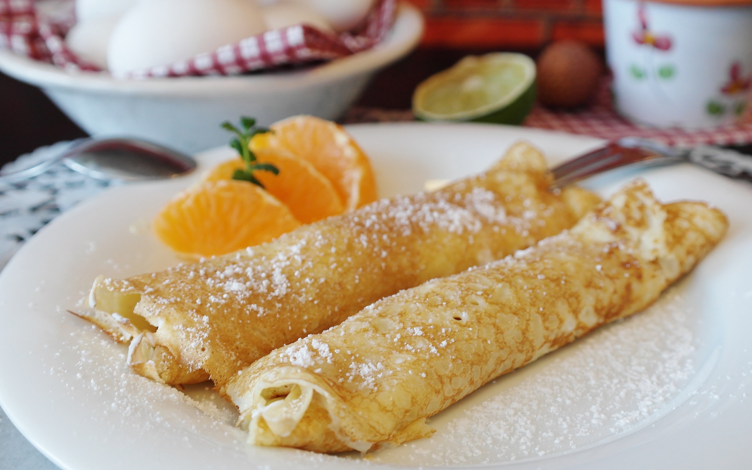 Блины с сахарной пудрой на тарелке с дольками мандарина