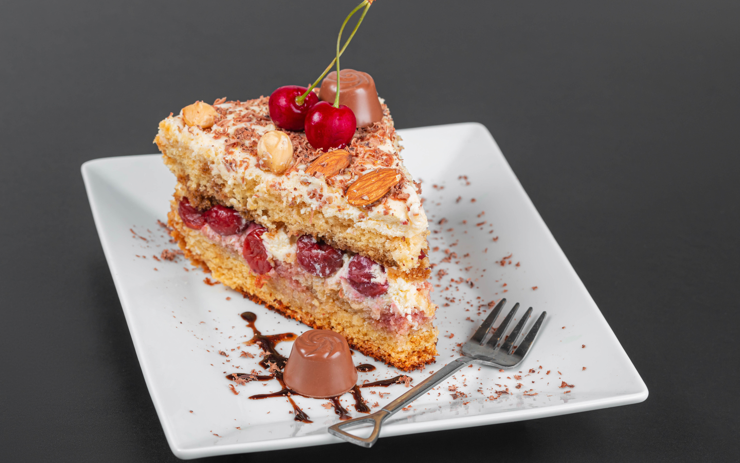 Кусок торта с ягодами вишни и миндальным орехом