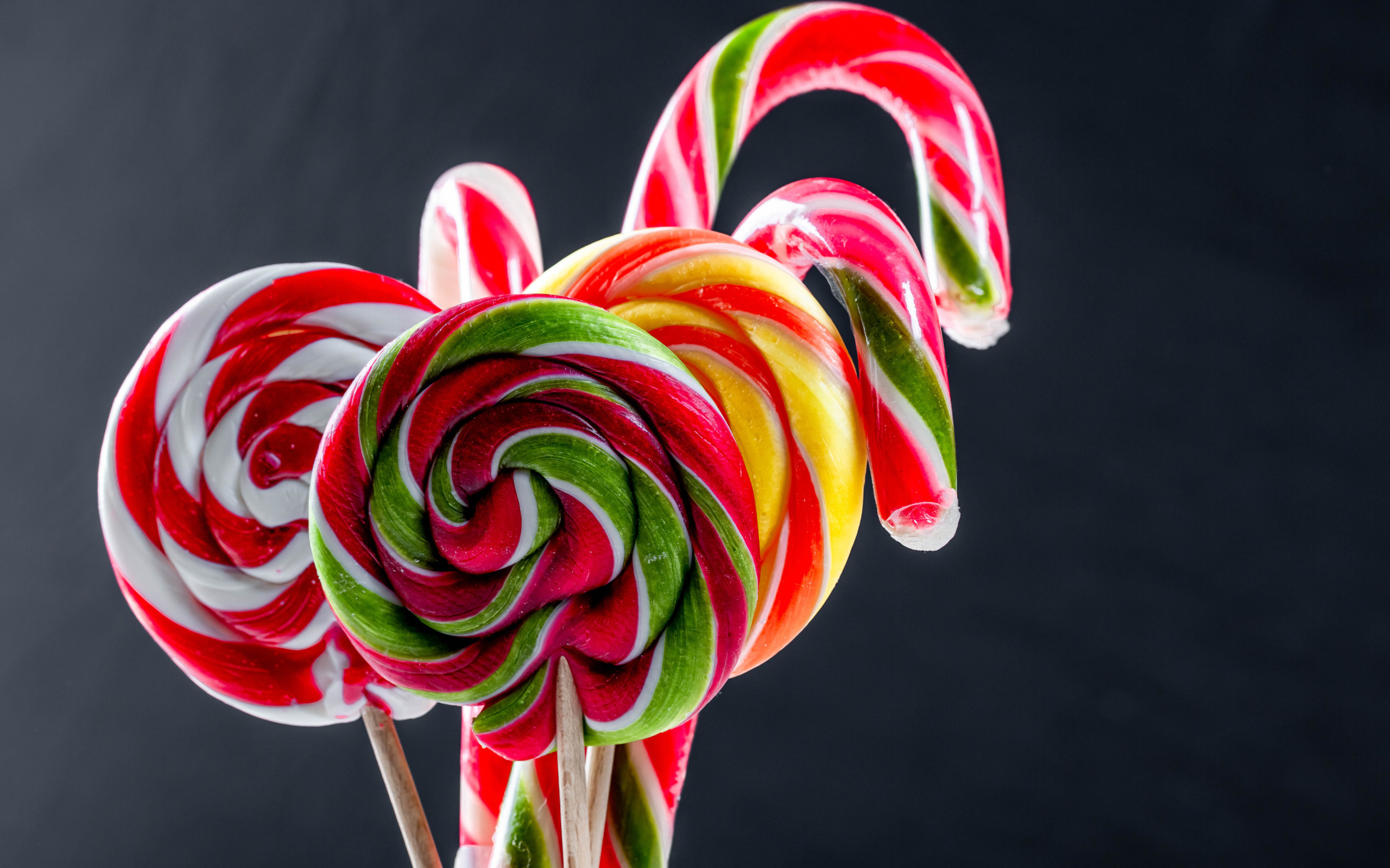 Вкусные разноцветные конфеты на палочке на сером фоне