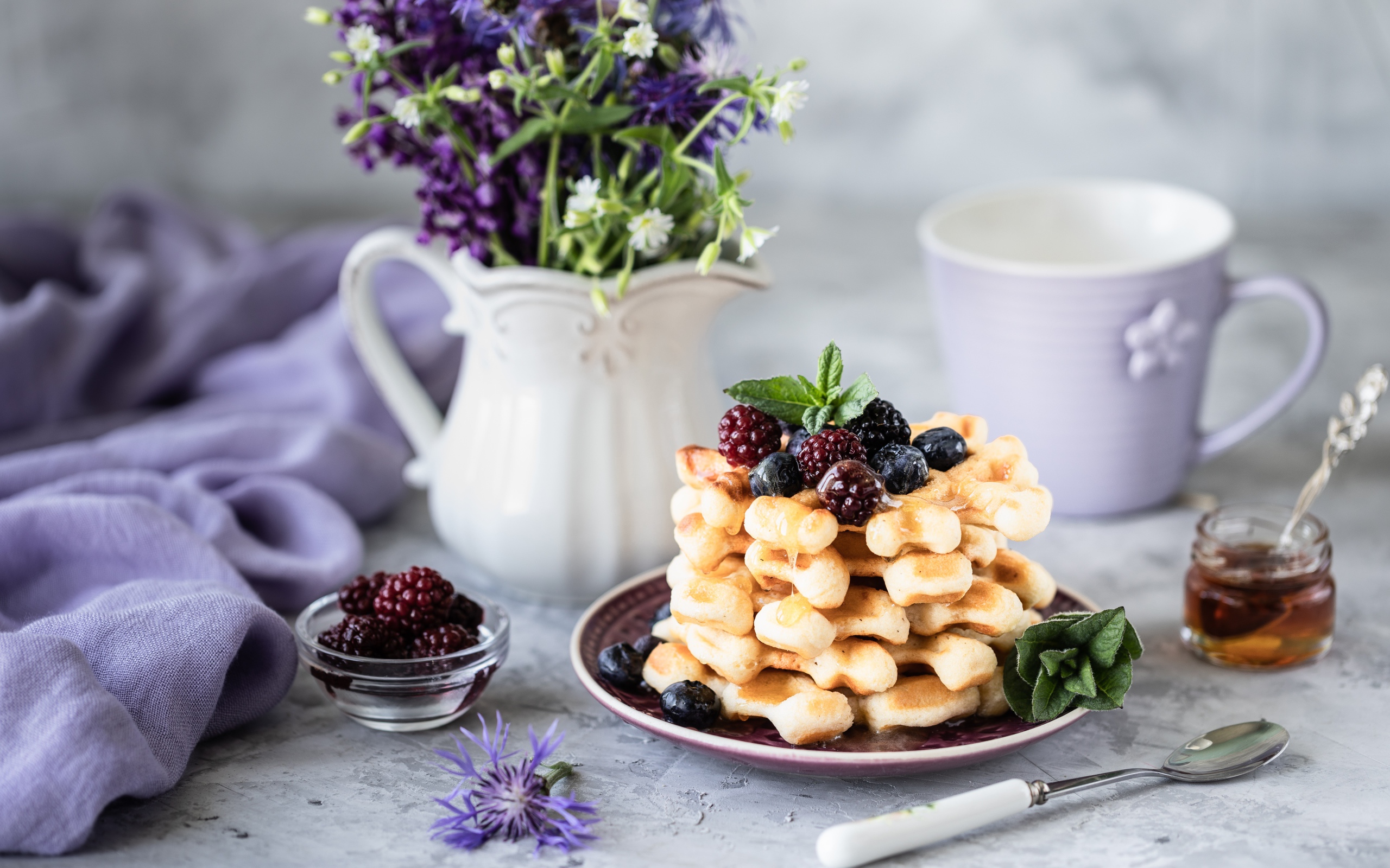 Вафли с ягодами черники и ежевики на столе с букетом