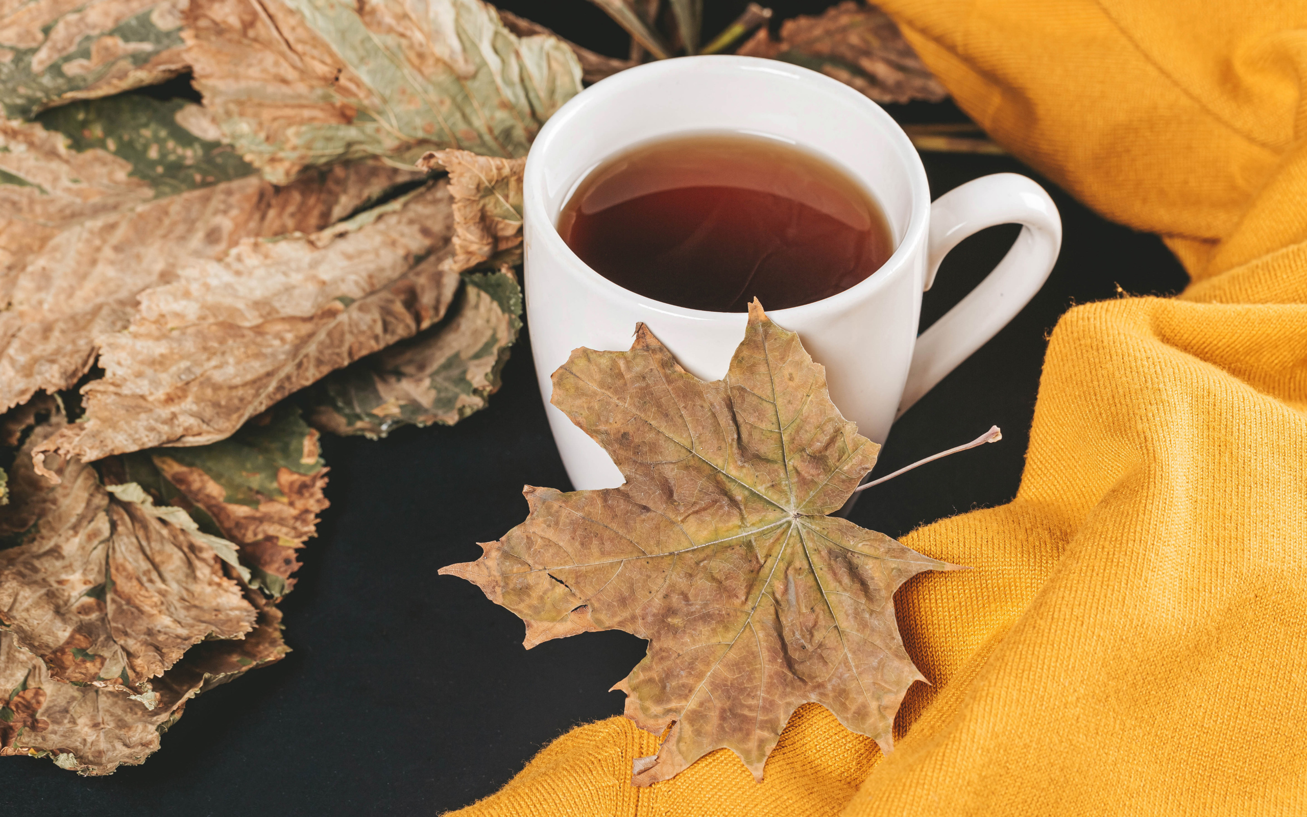 Чашка горячего чая на столе с сухими листьями