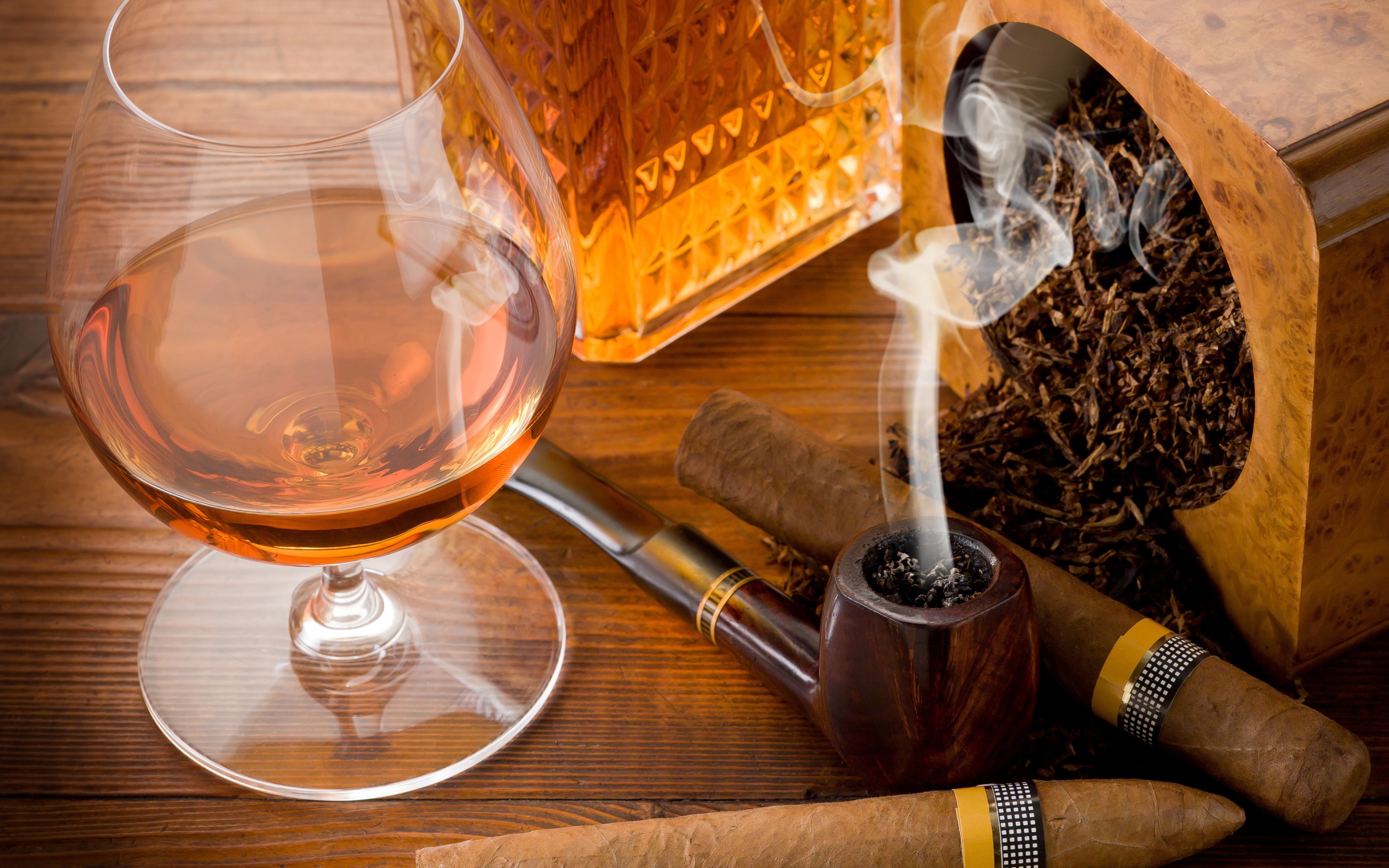 Бокал коньяка на столе с трубкой и сигарой 