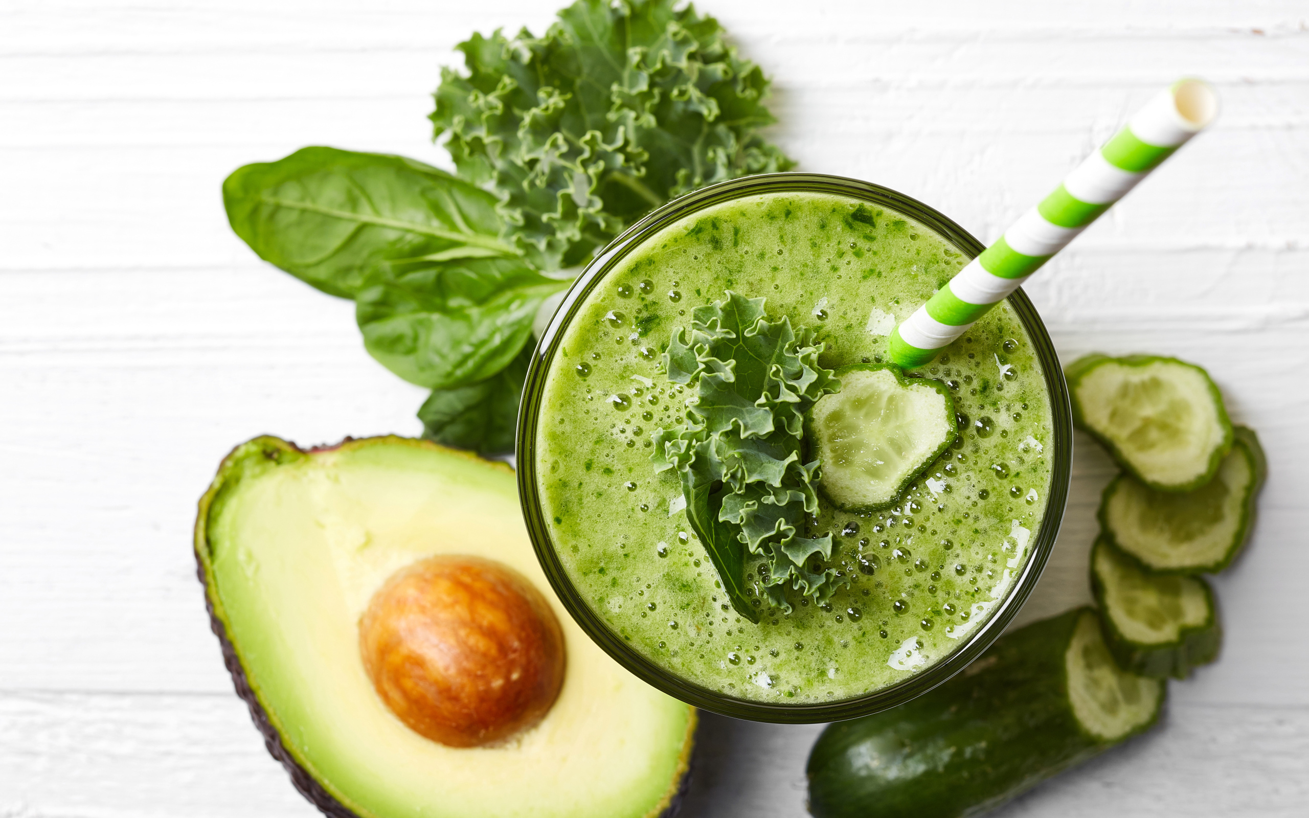 Зеленый смузи на столе с огурцом, авокадо и зеленью