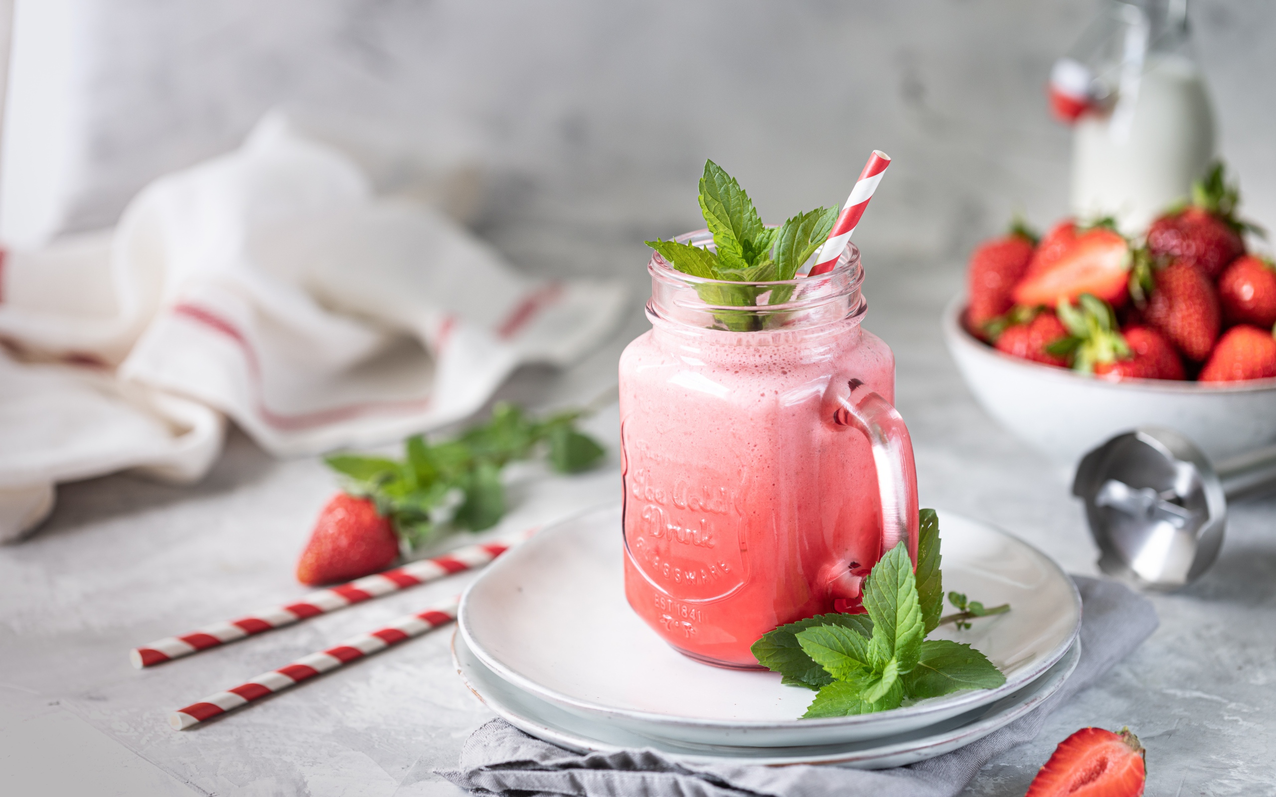 Смузи с клубникой в банке с трубочкой и листьями мяты