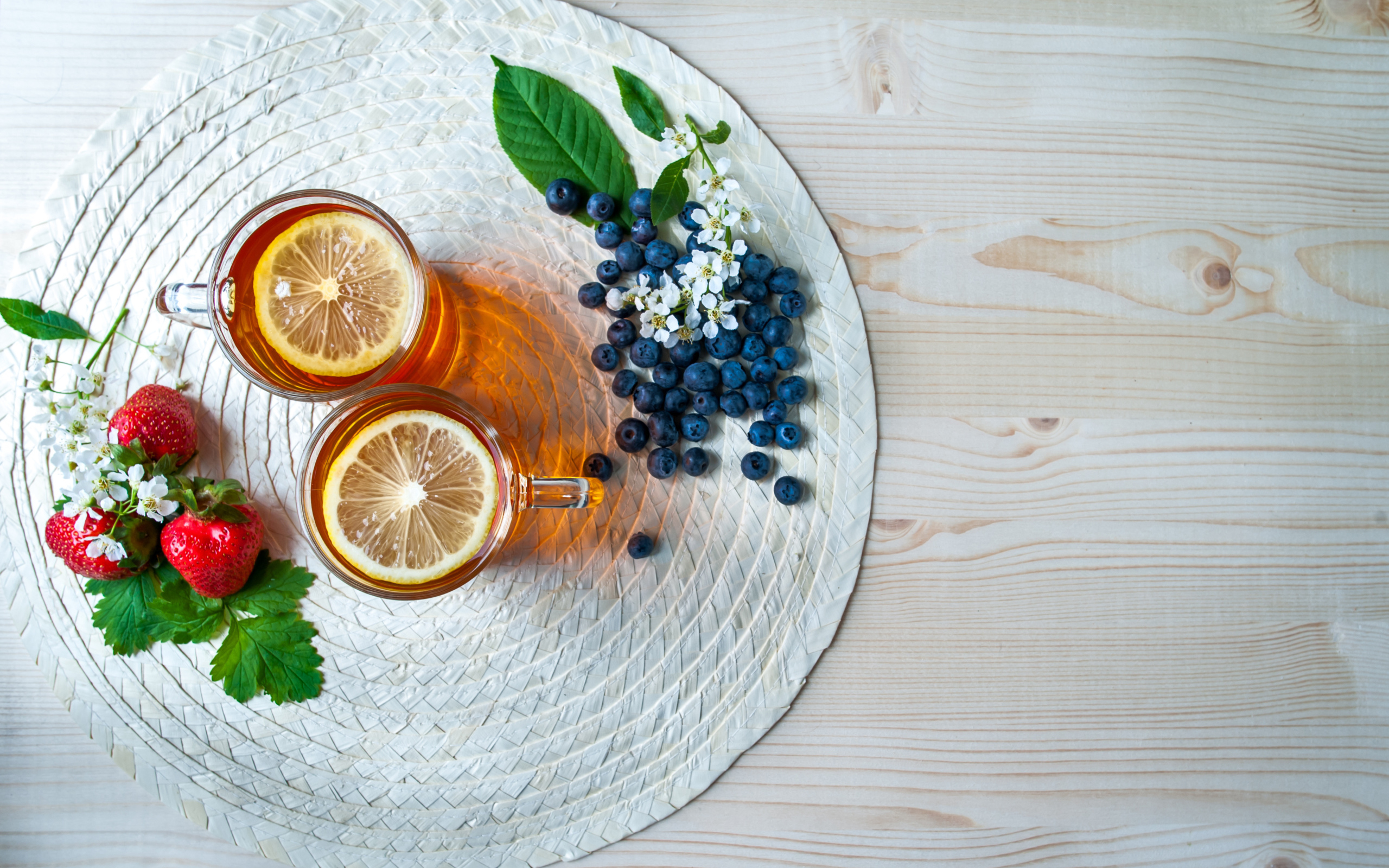 Чай с лимоном на столе с ягодами клубники и черники