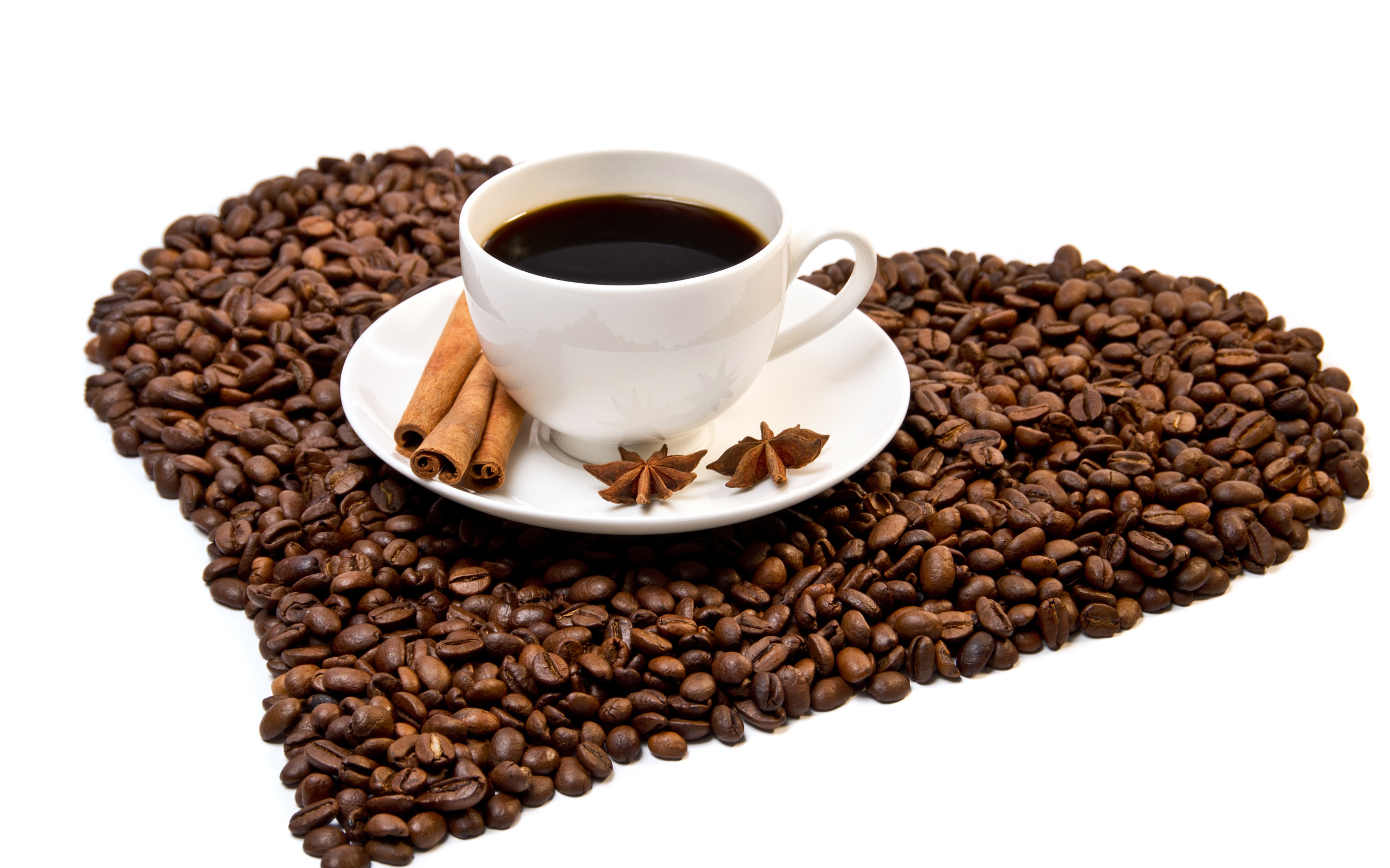 Белая чашка с корицей и бадьяном стоит на кофейных зернах на белом фоне