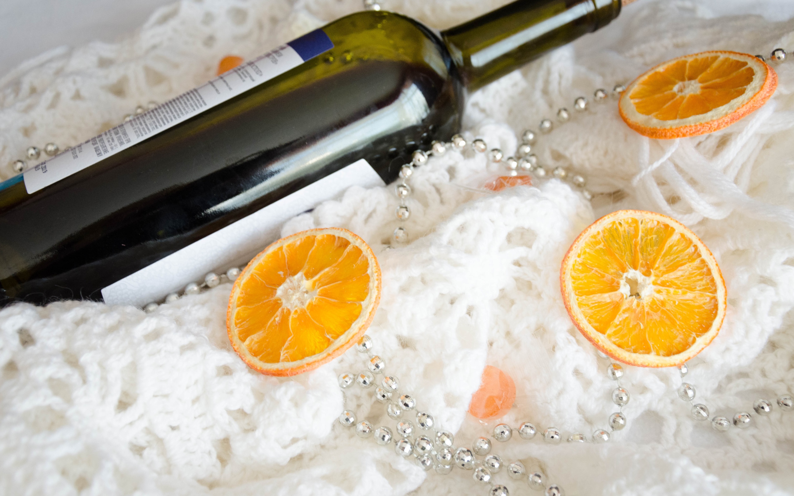 Бутылка вина и кусочки апельсина на белом платке 