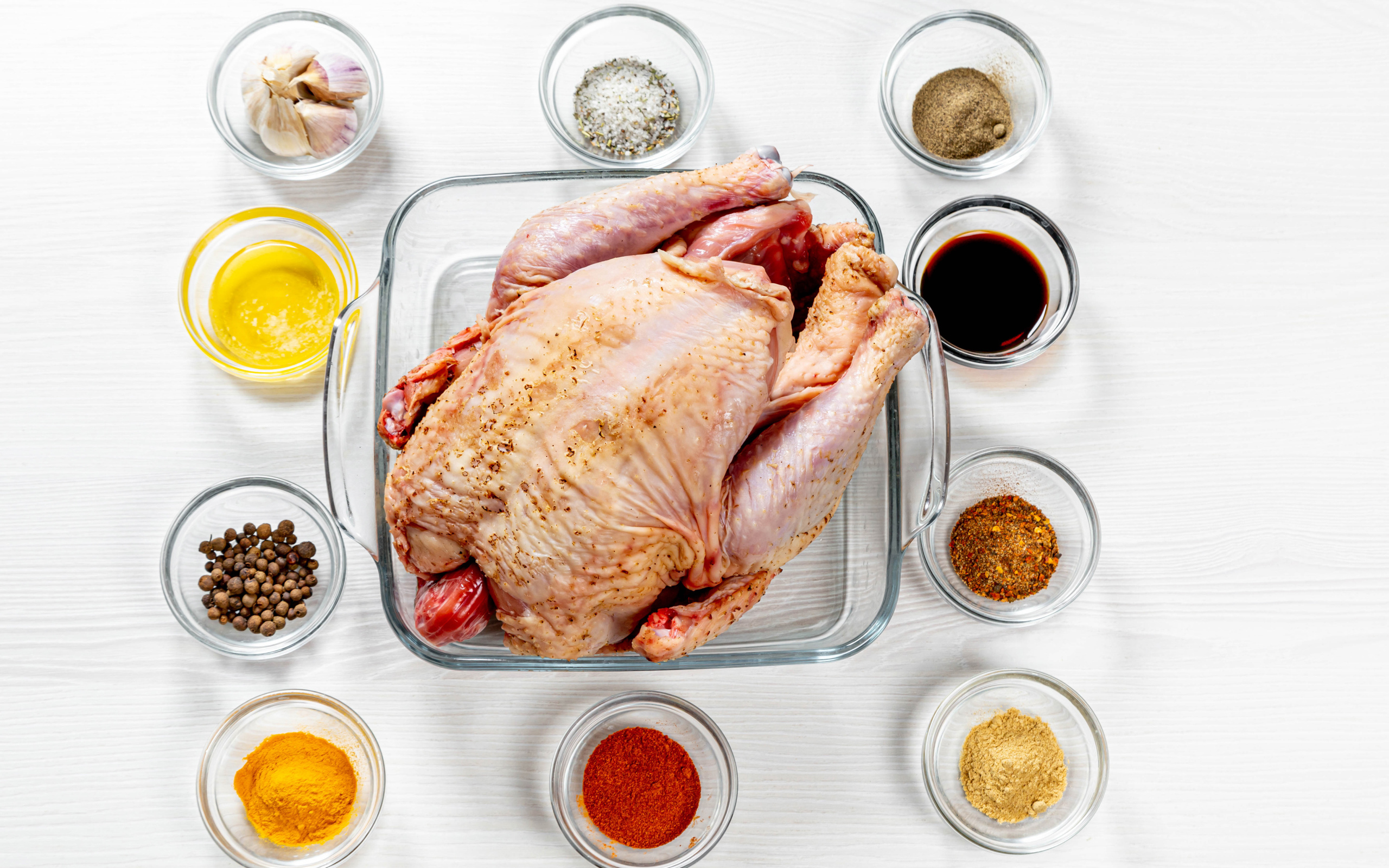 Свежая курица на противне на столе со специями 
