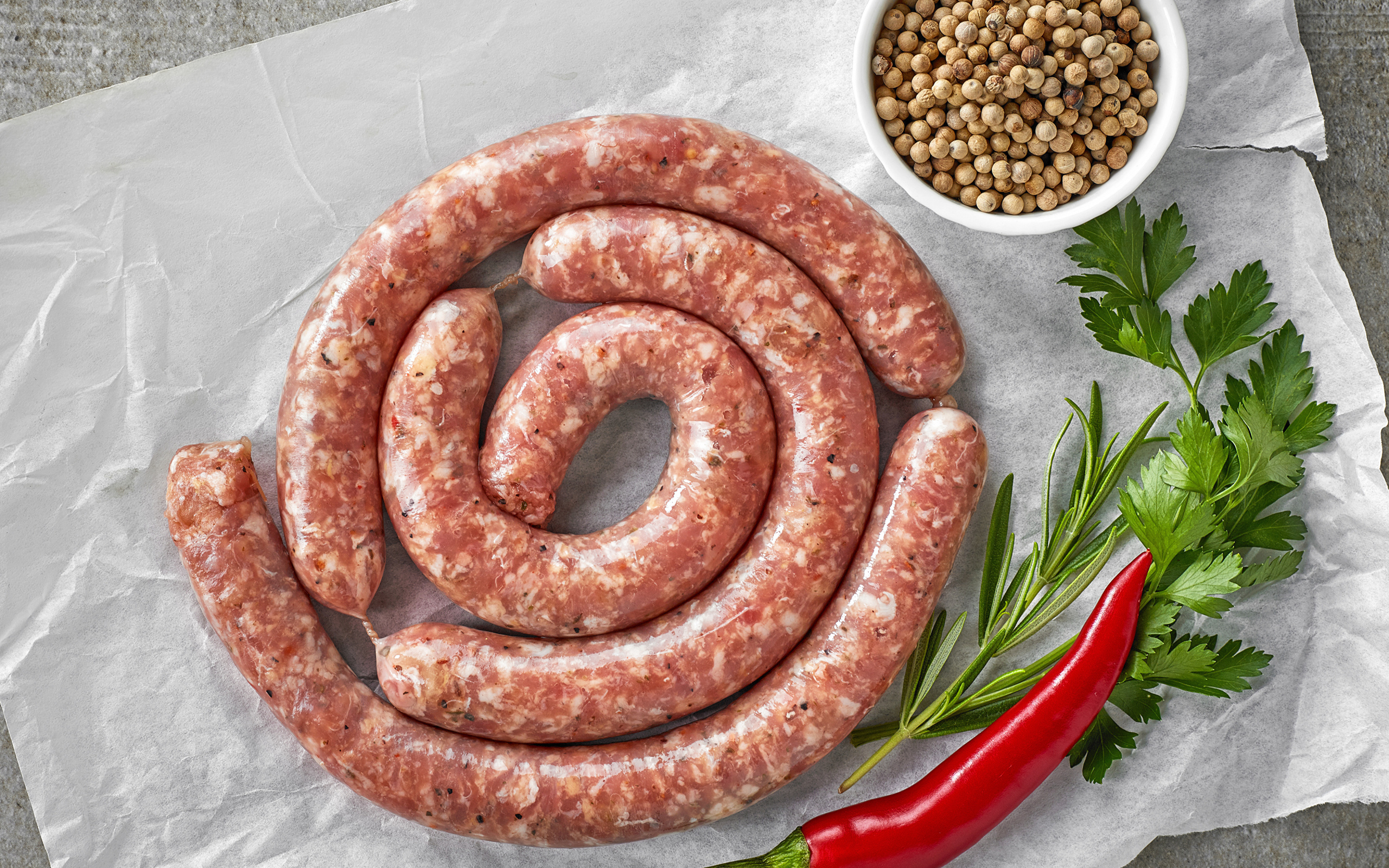 Домашняя колбаса на столе с зеленью и перцем