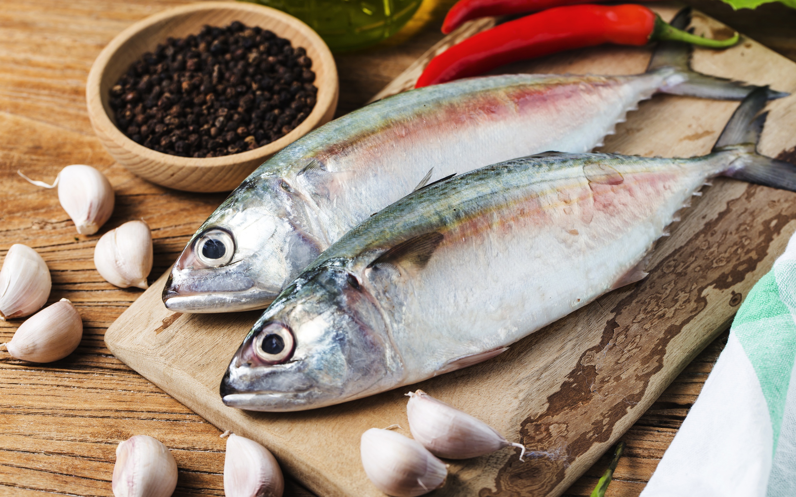 Свежая рыба лежит на доске с чесноком и специями