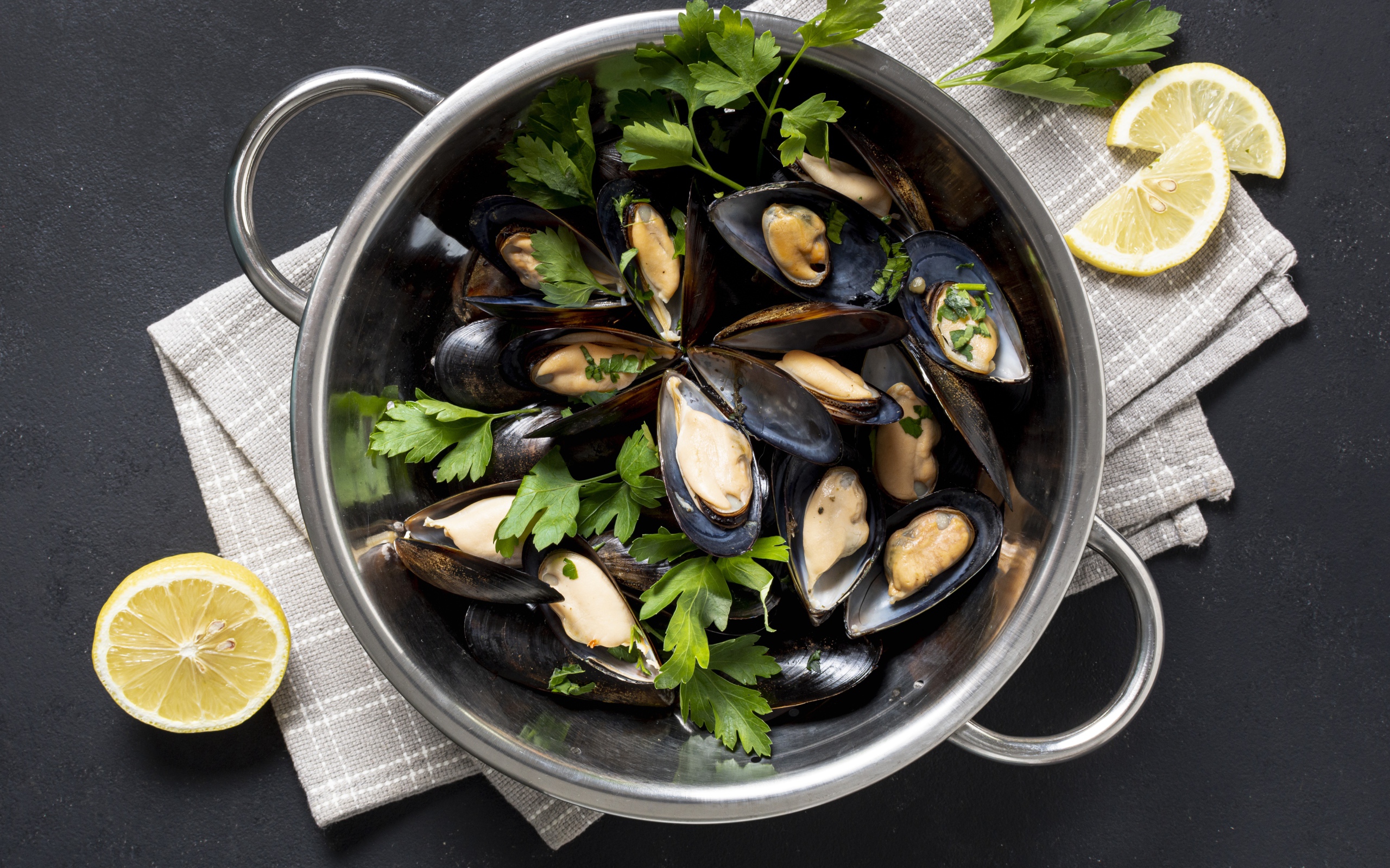 Свежие мидии в кастрюле с зеленью петрушки 