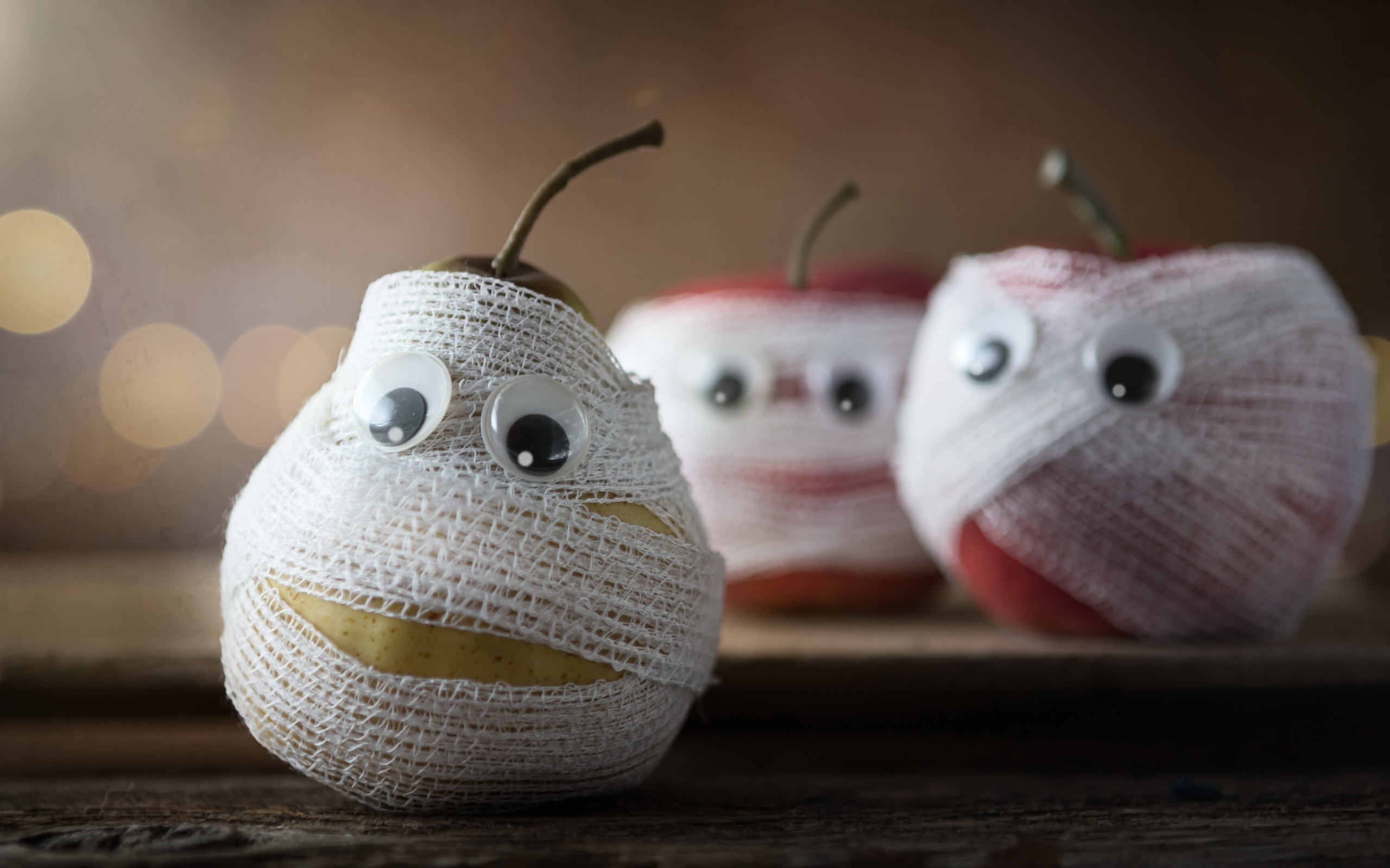 Груши и яблоки в бинтах на столе 