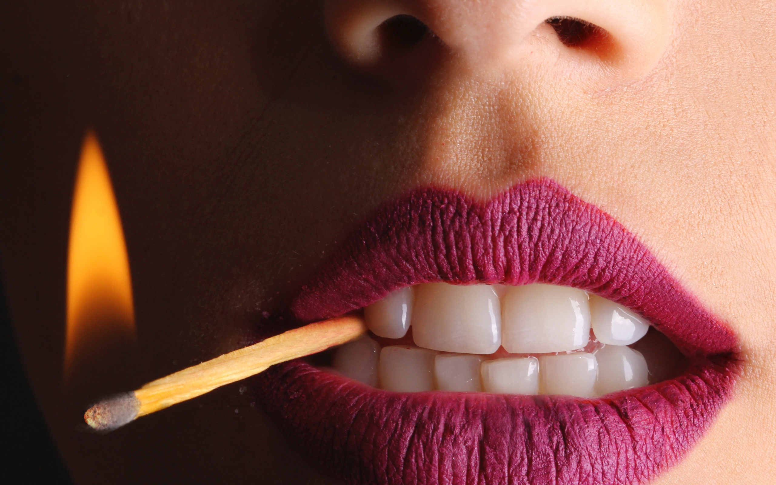 Зажженная спичка в зубах у девушки 