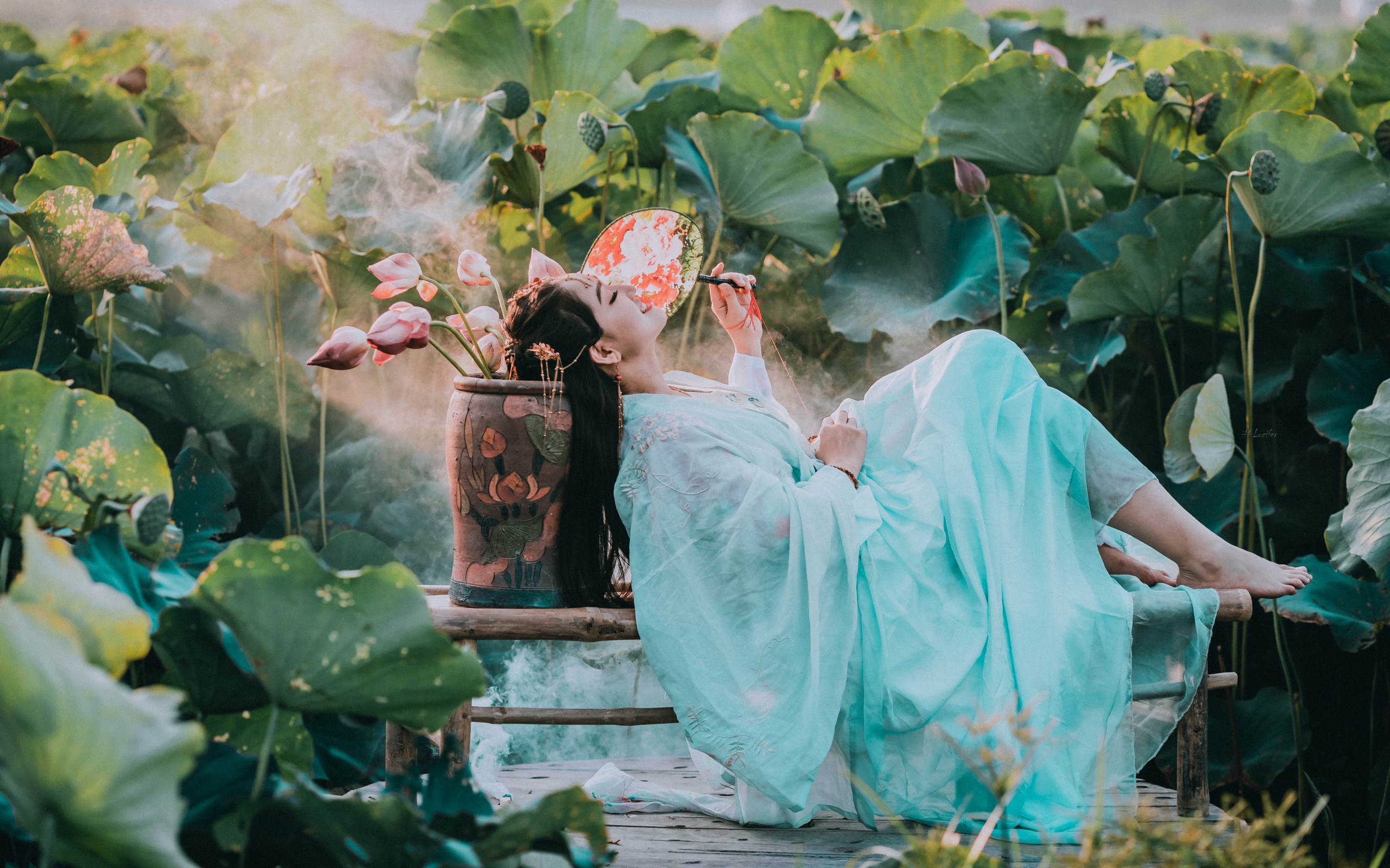 Девушка азиатка в красивом голубом платье на поле лотосов