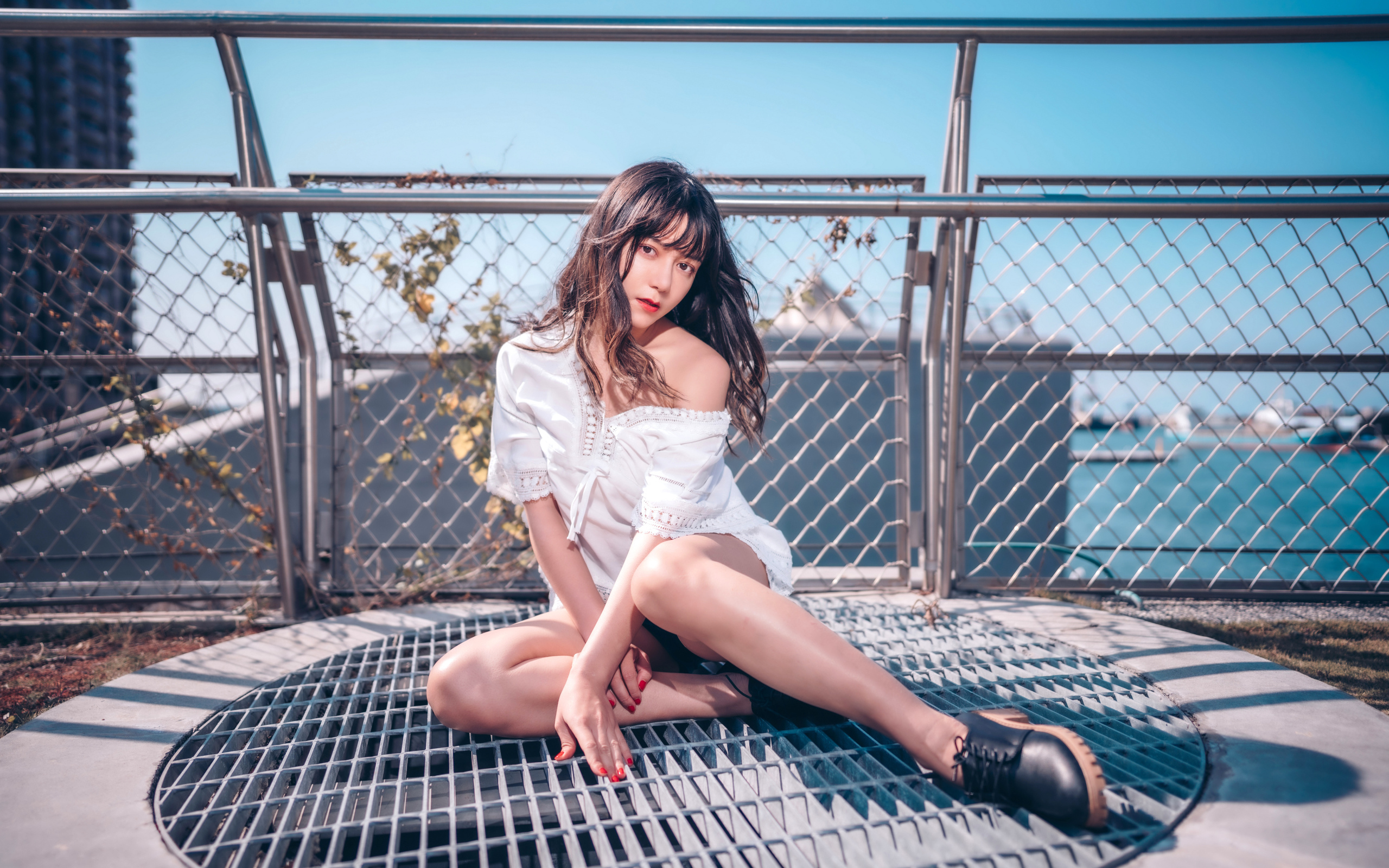 Девушка азиатка в белом наряде сидит на сетке