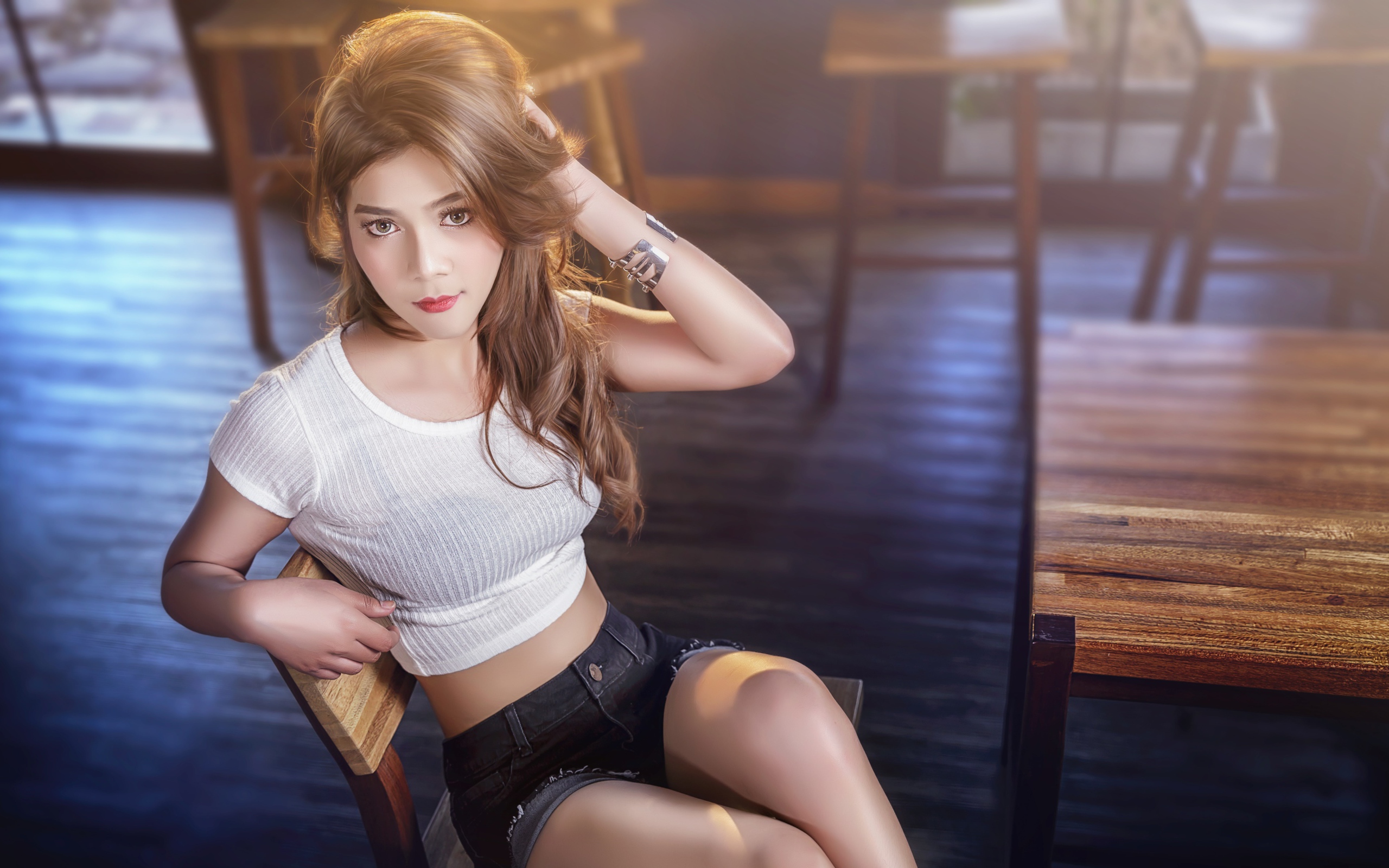 Девушка азиатка сидит на деревянном стуле в кафе