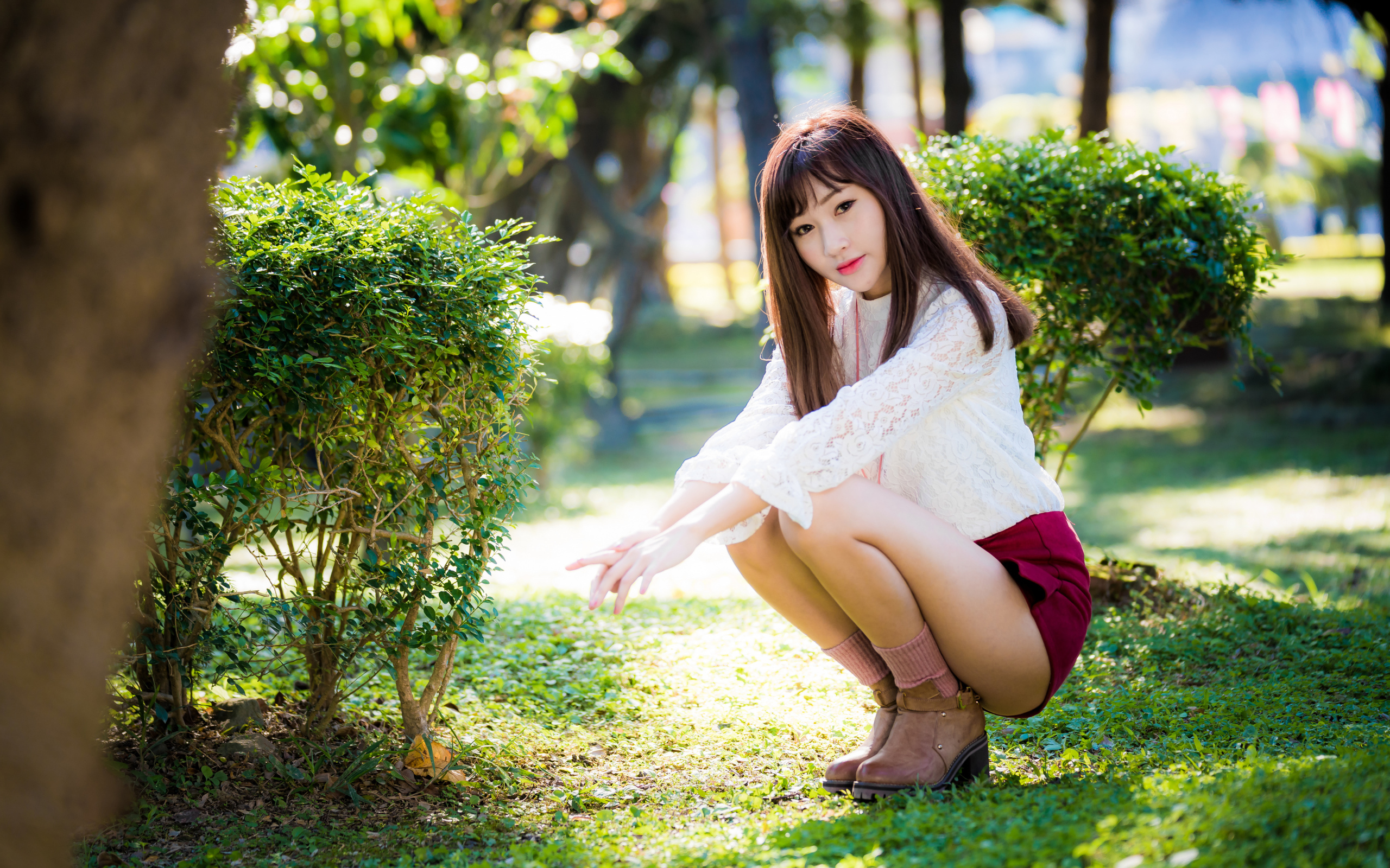 Девушка азиатка сидит на корточках в парке