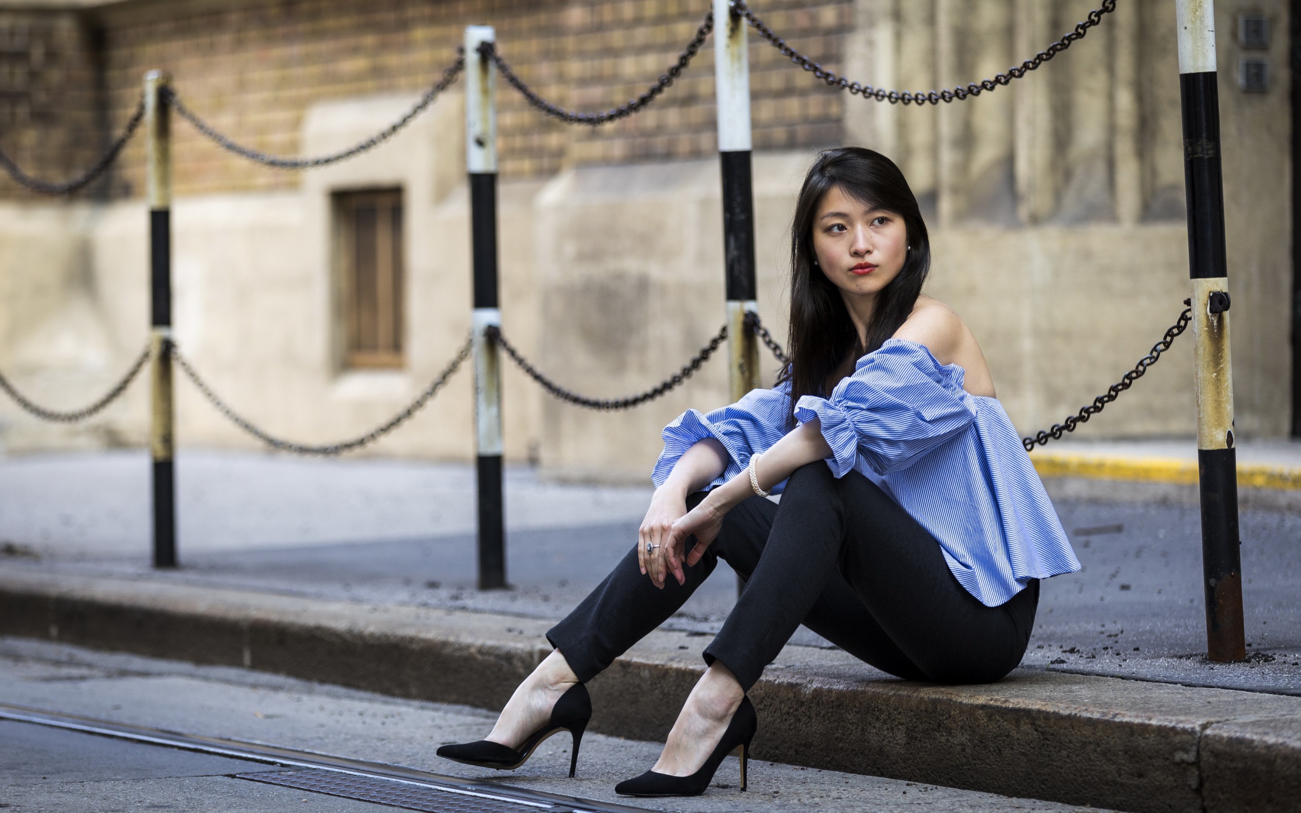 Красивая девушка азиатка в черных брюках сидит на земле