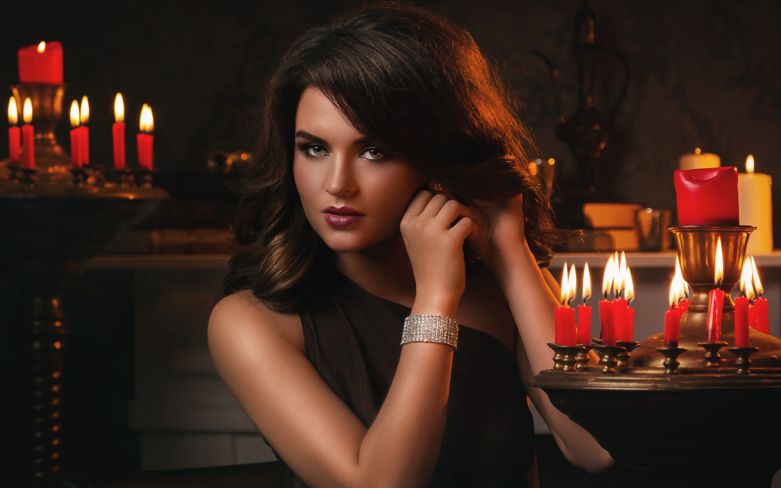 Красивая брюнетка в черном платье и зажженными свечами
