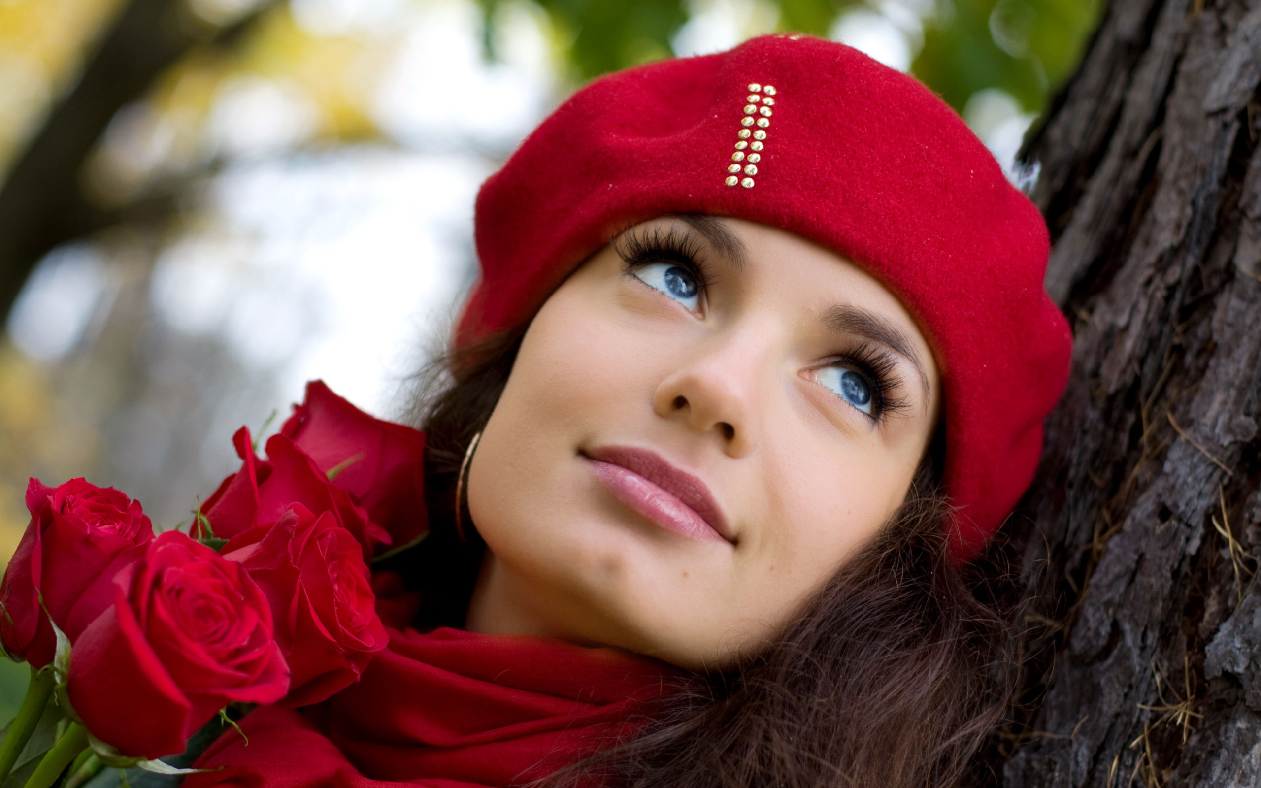 Красивая девушка в красном берете с букетом роз у дерева