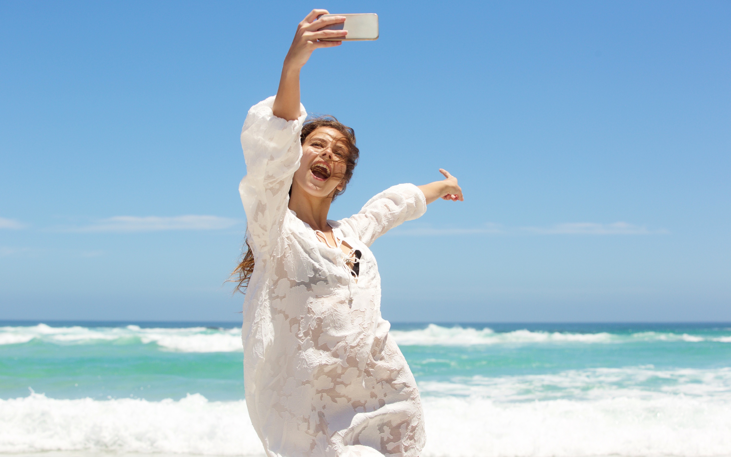 Красивая девушка в белом платье делает селфи на море 