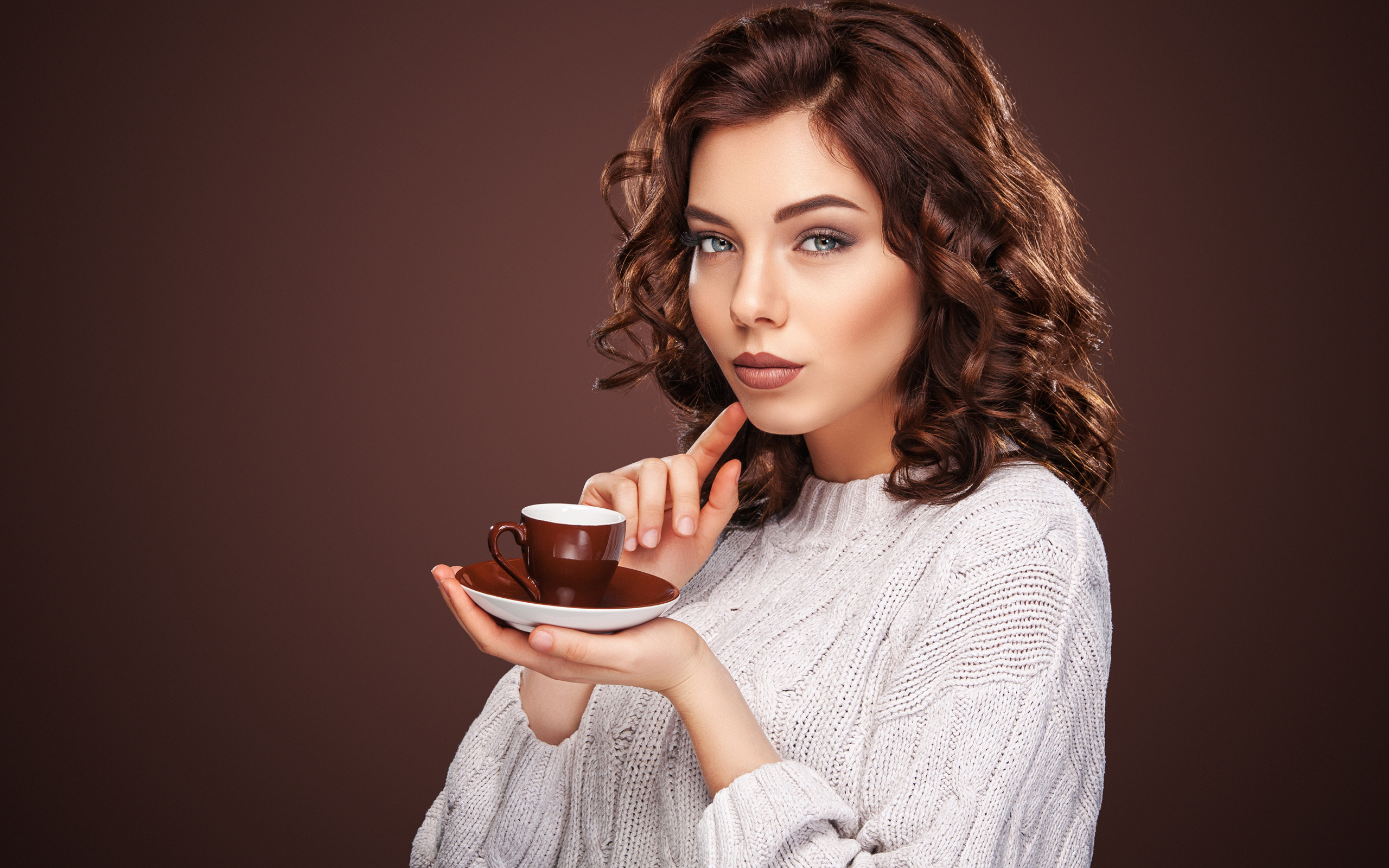 Красивая девушка в белом свитере с чашкой кофе
