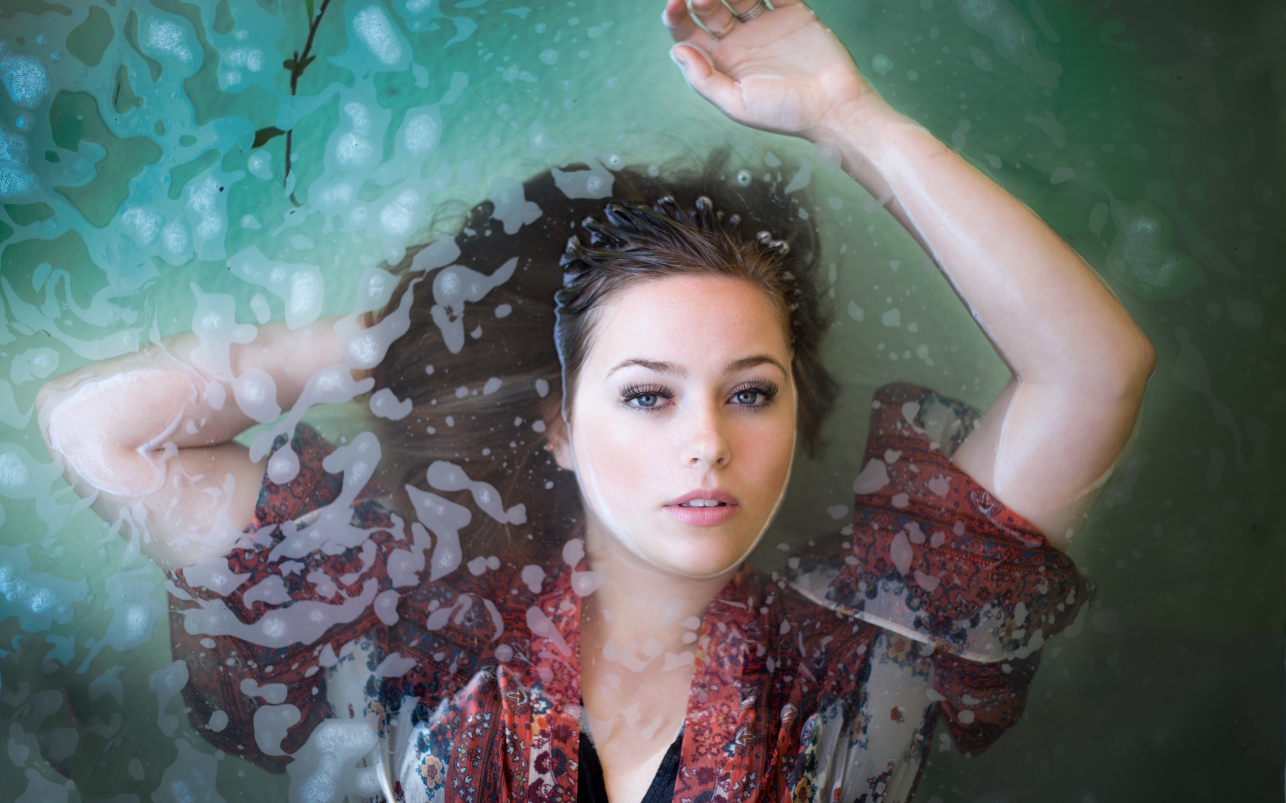 Красивая девушка лежит в одежде в воде 