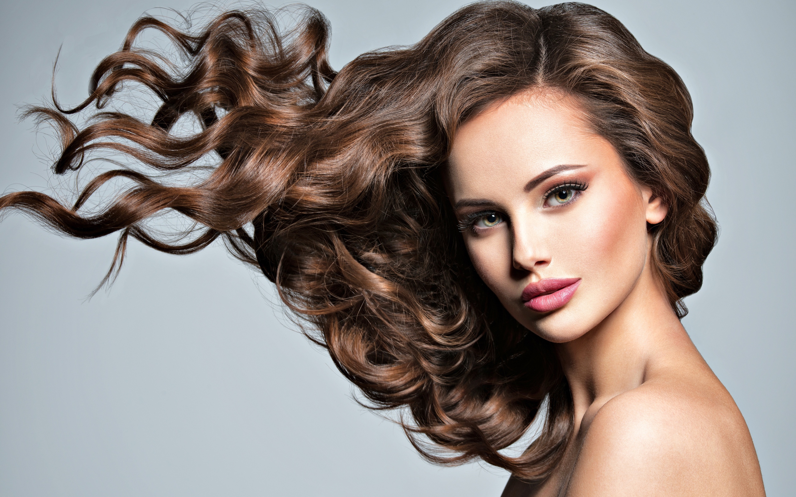 Красивая девушка модель с волнистыми волосами на сером фоне