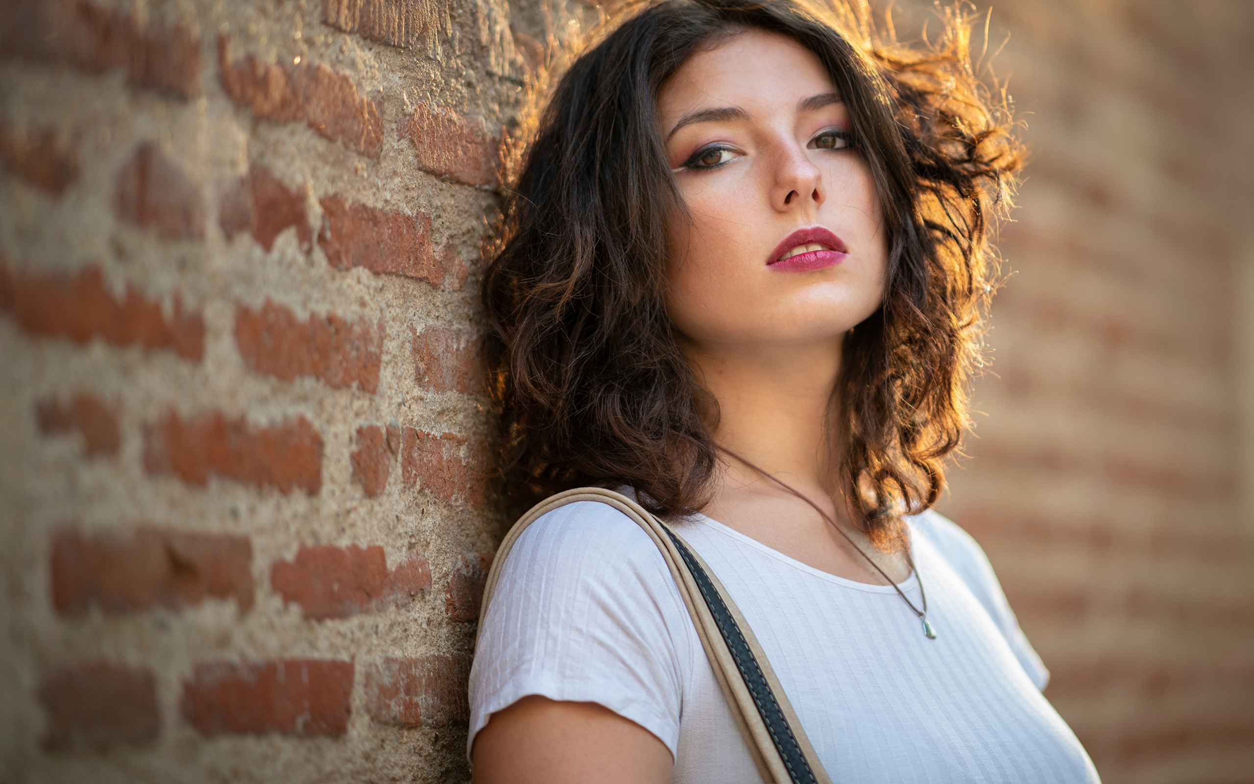 Красивая девушка стоит у стены 