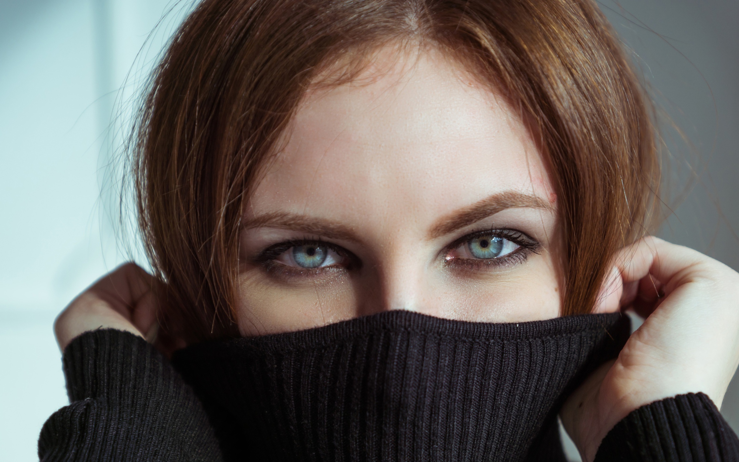Красивая девушка с голубыми глазами закрыла лицо свитером 