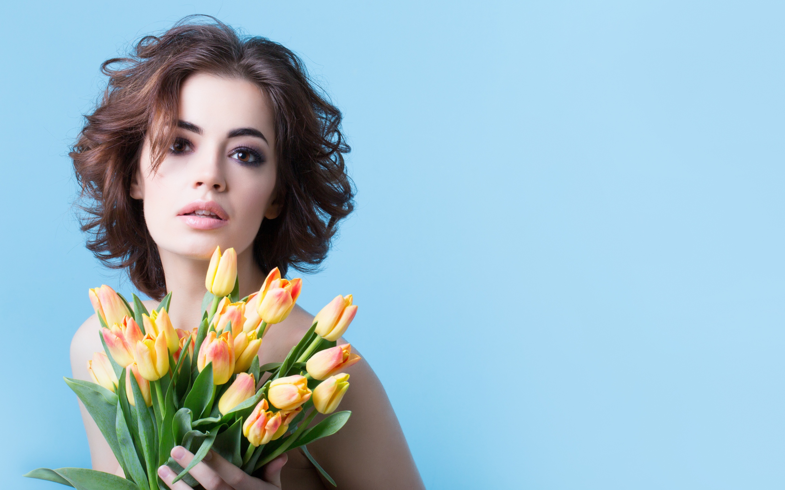 Кареглазая шатенка с букетом тюльпанов на голубом фоне