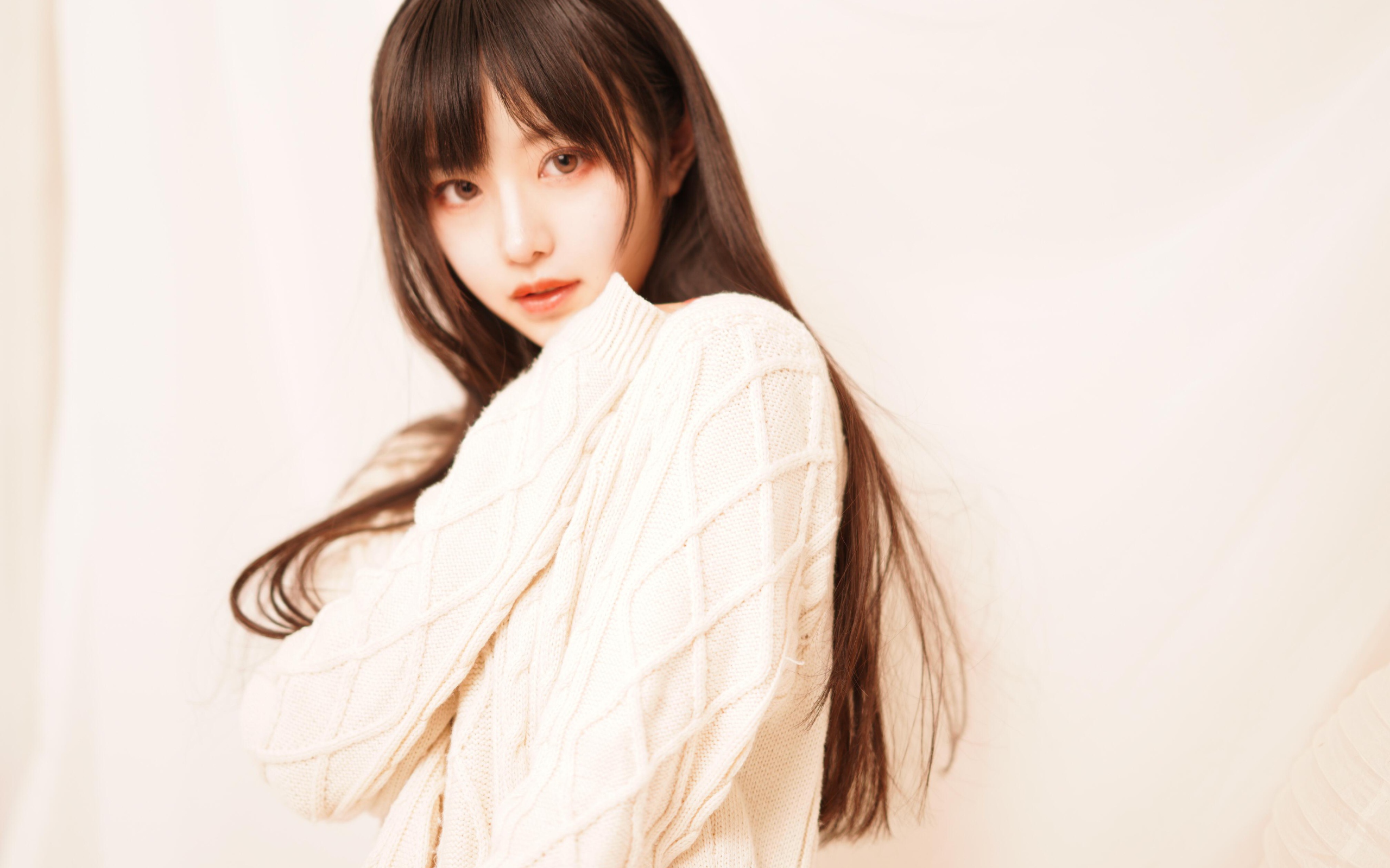 Милая азиатка в белом свитере на розовом фоне