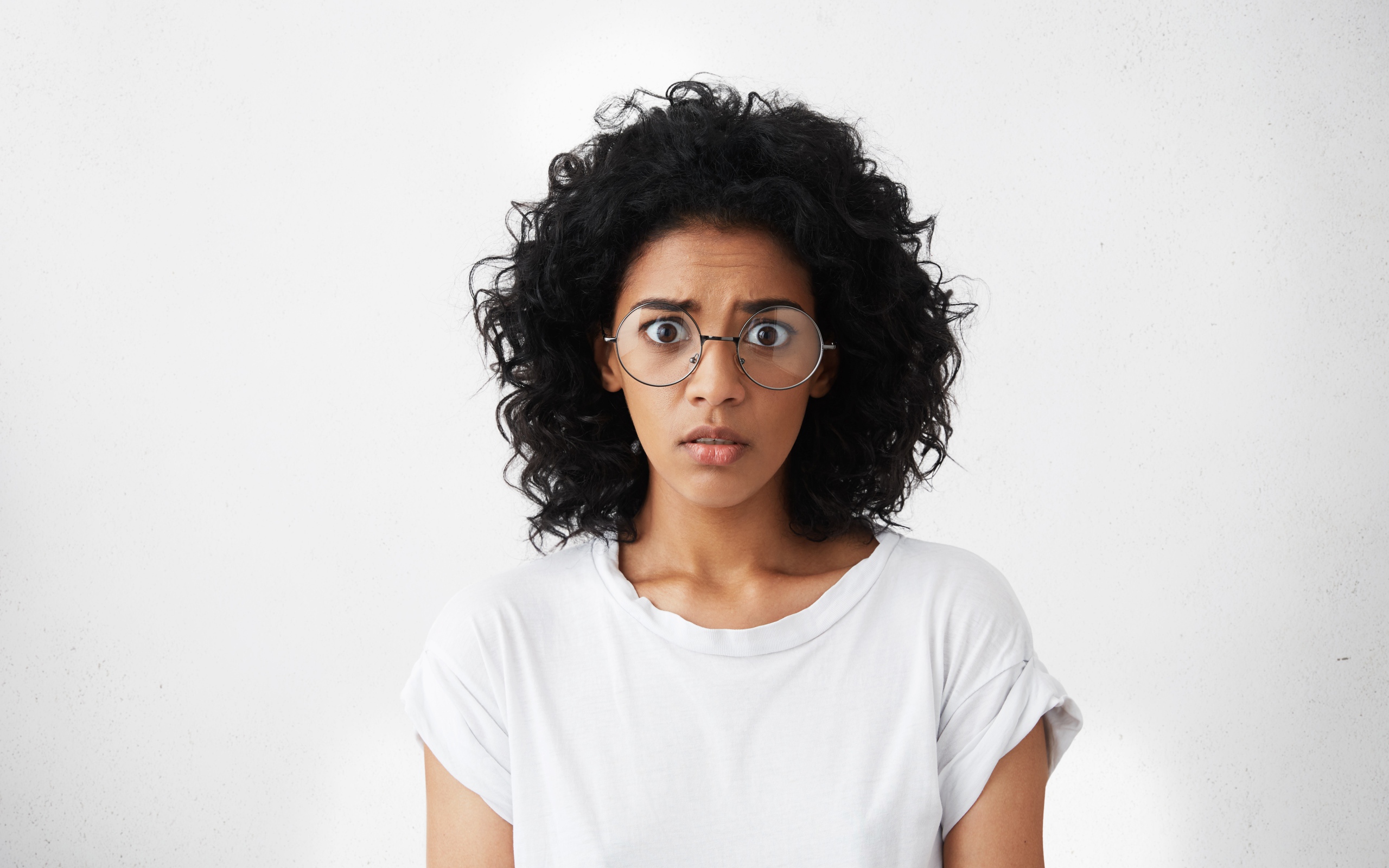 Темноволосая девушка в белой футболке на сером фоне